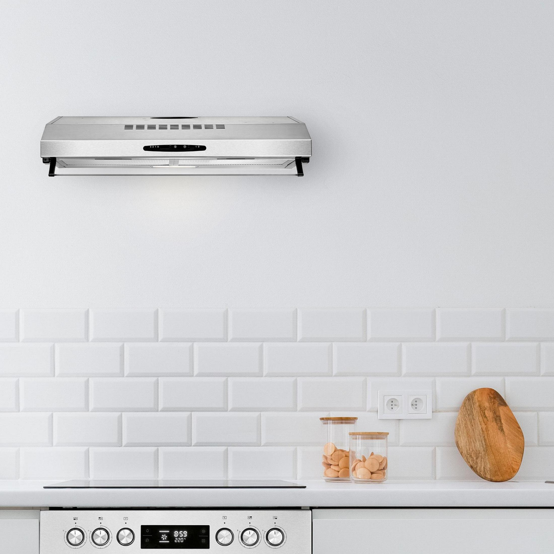 Scena di cucina con cappa in acciaio inox. Piastrelle bianche.