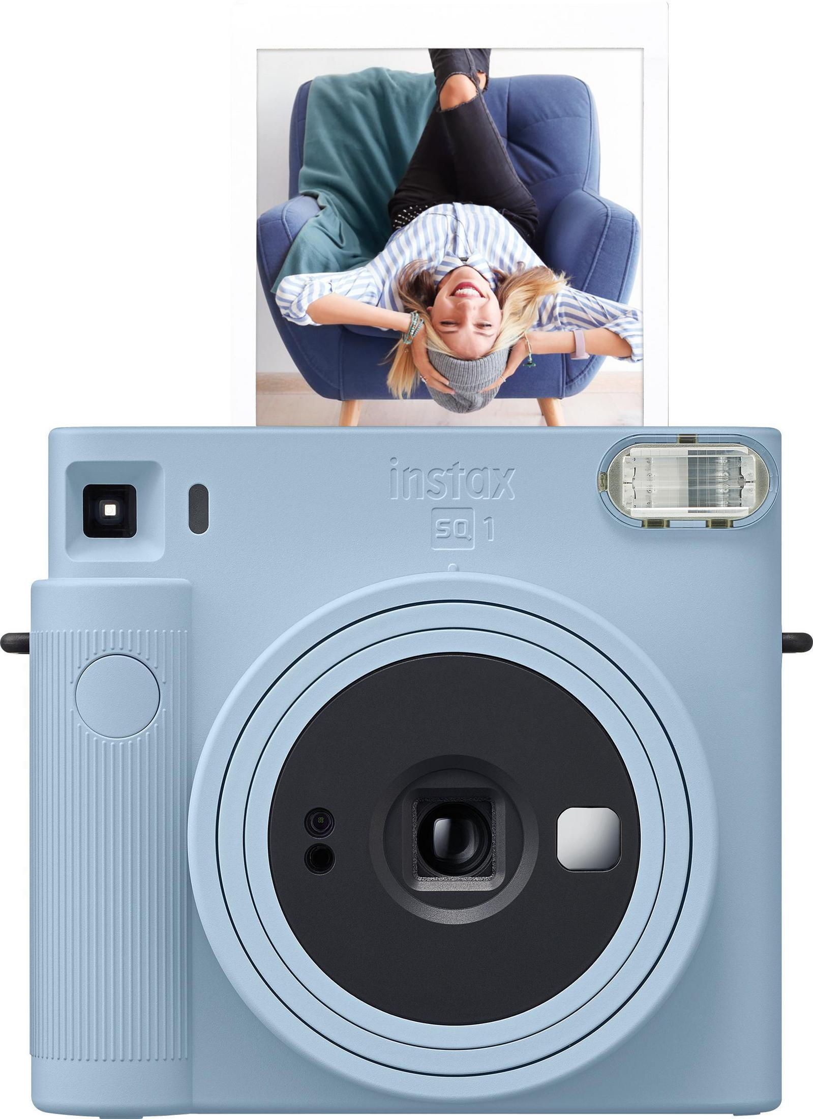 Hellblaue Instax SQ1 Kamera mit einem Foto einer lächelnden Person, die auf einem Stuhl liegt.
