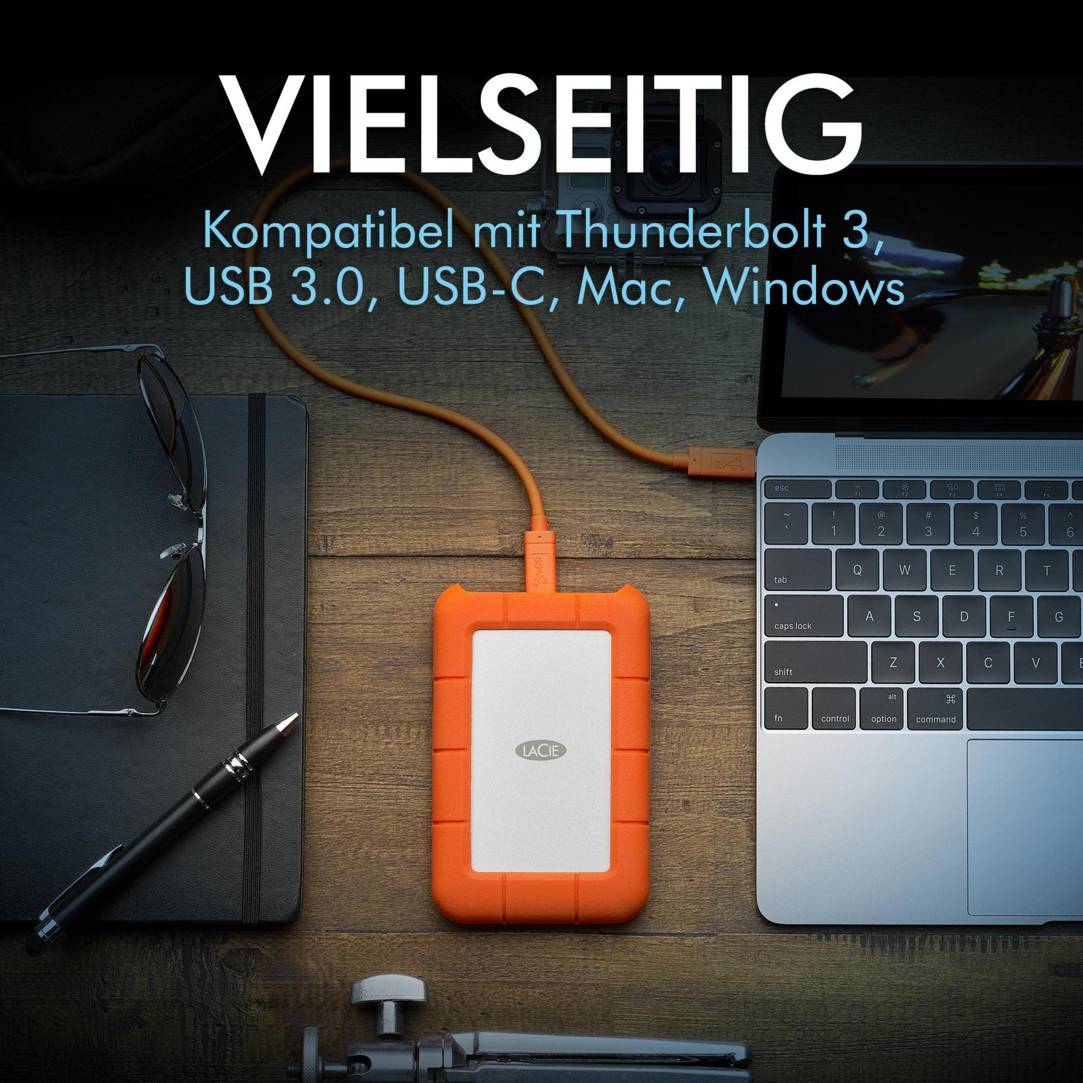 Ein Schreibtisch mit Laptop, Festplatte, Notizbuch, Stift und Kameraständer.