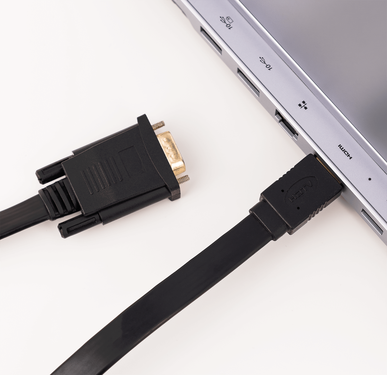 Czarny kabel HDMI podłączony do laptopa obok kabla VGA.