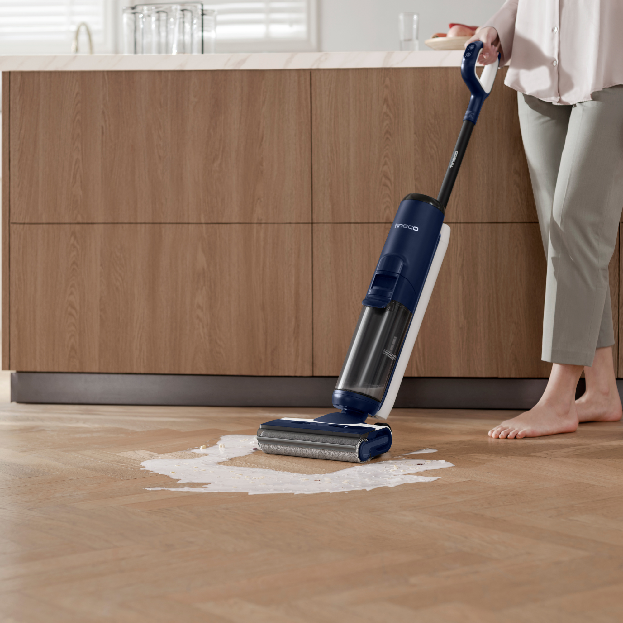Persona limpiando suelo de madera con limpiador azul y blanco, dejando rastro blanco.