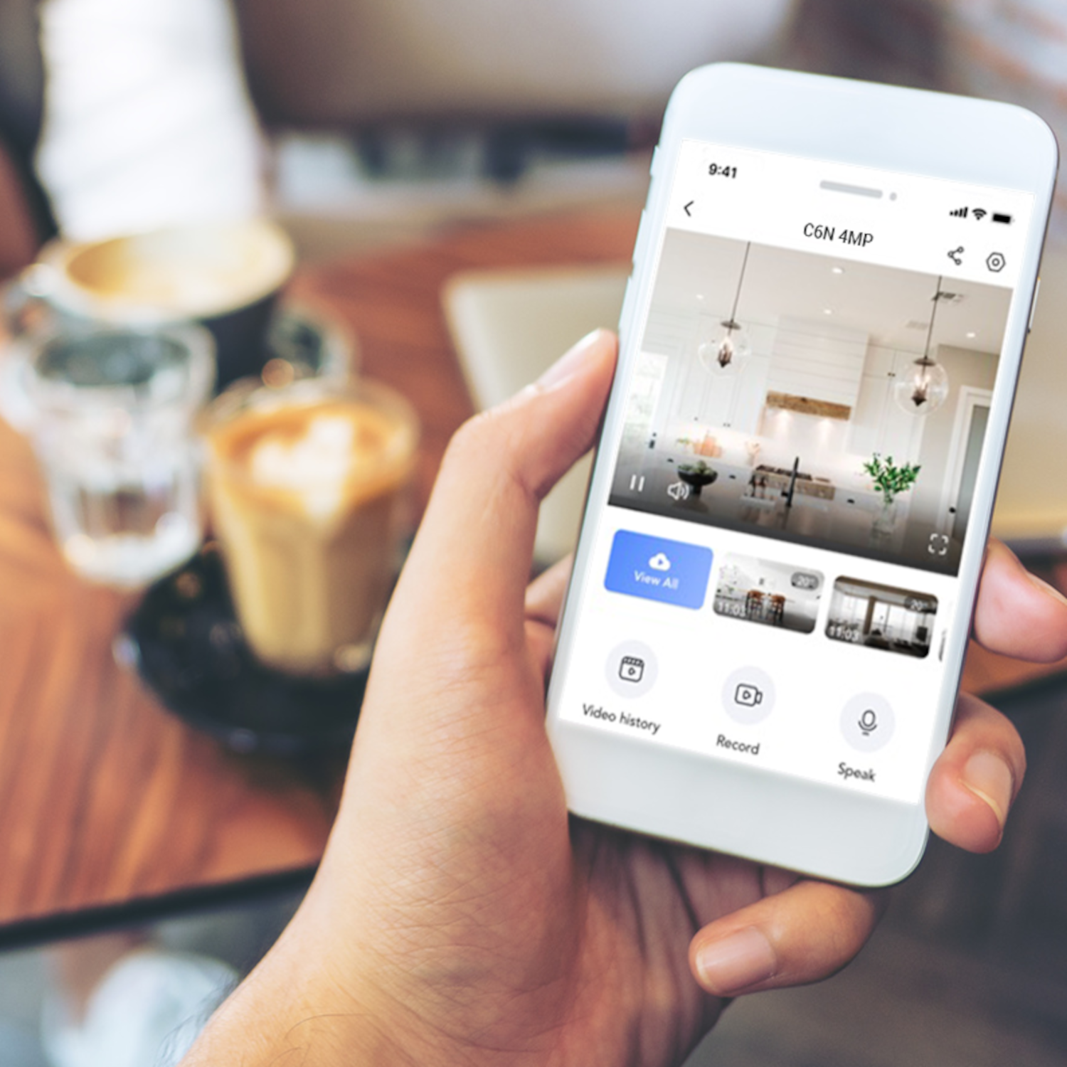 Ręka trzymająca biały telefon z ekranem pokazującym widok z kamery.