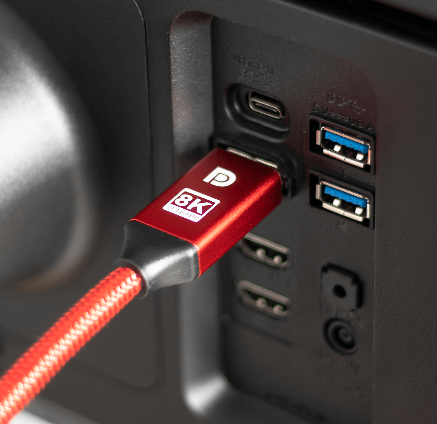 Czerwony kabel HDMI 8K podłączony do czarnego urządzenia. Urządzenie ma porty USB.