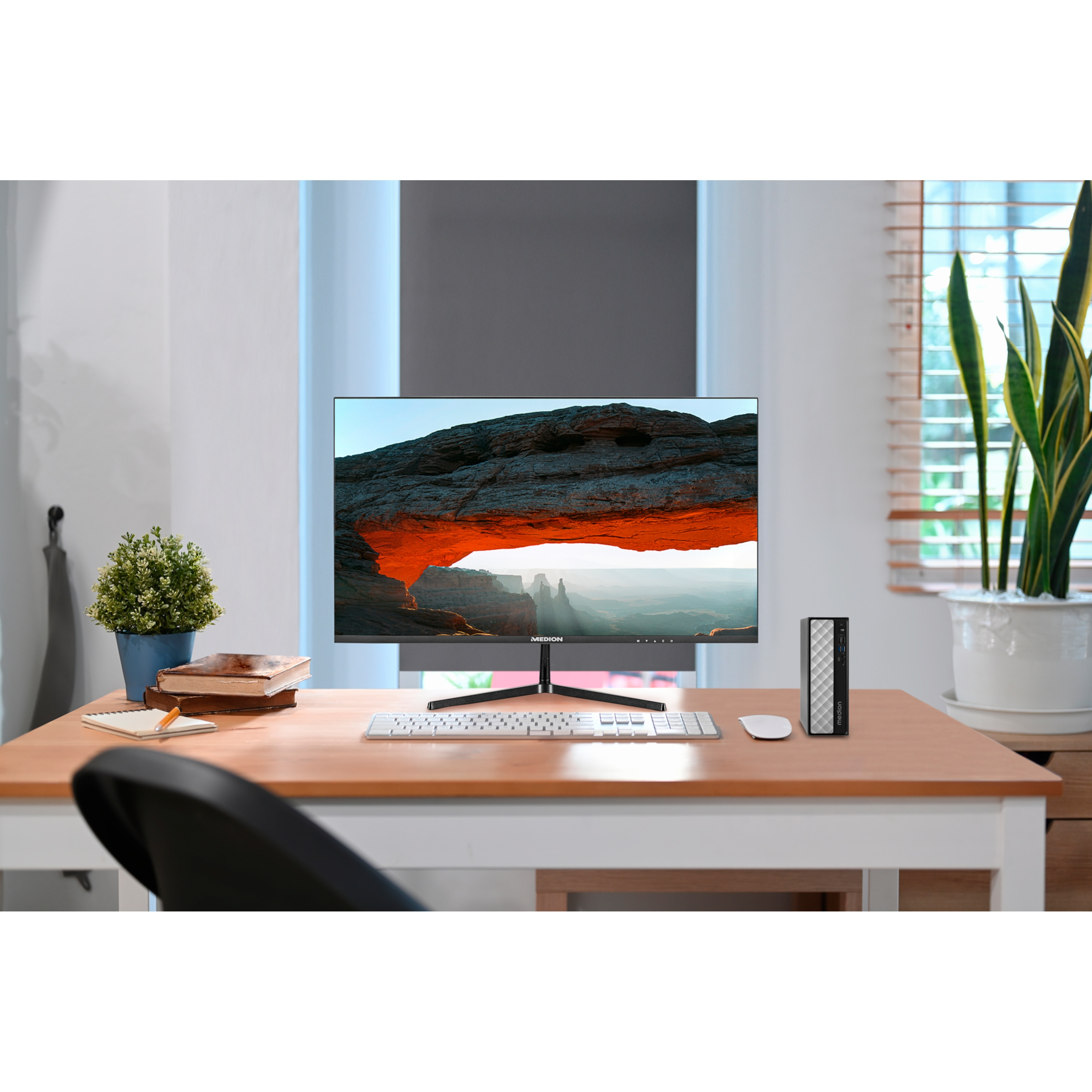 Konfiguracja komputera na drewnianym biurku. Zawiera monitor, obudowę komputera, klawiaturę, mysz i roślinę ozdobną.