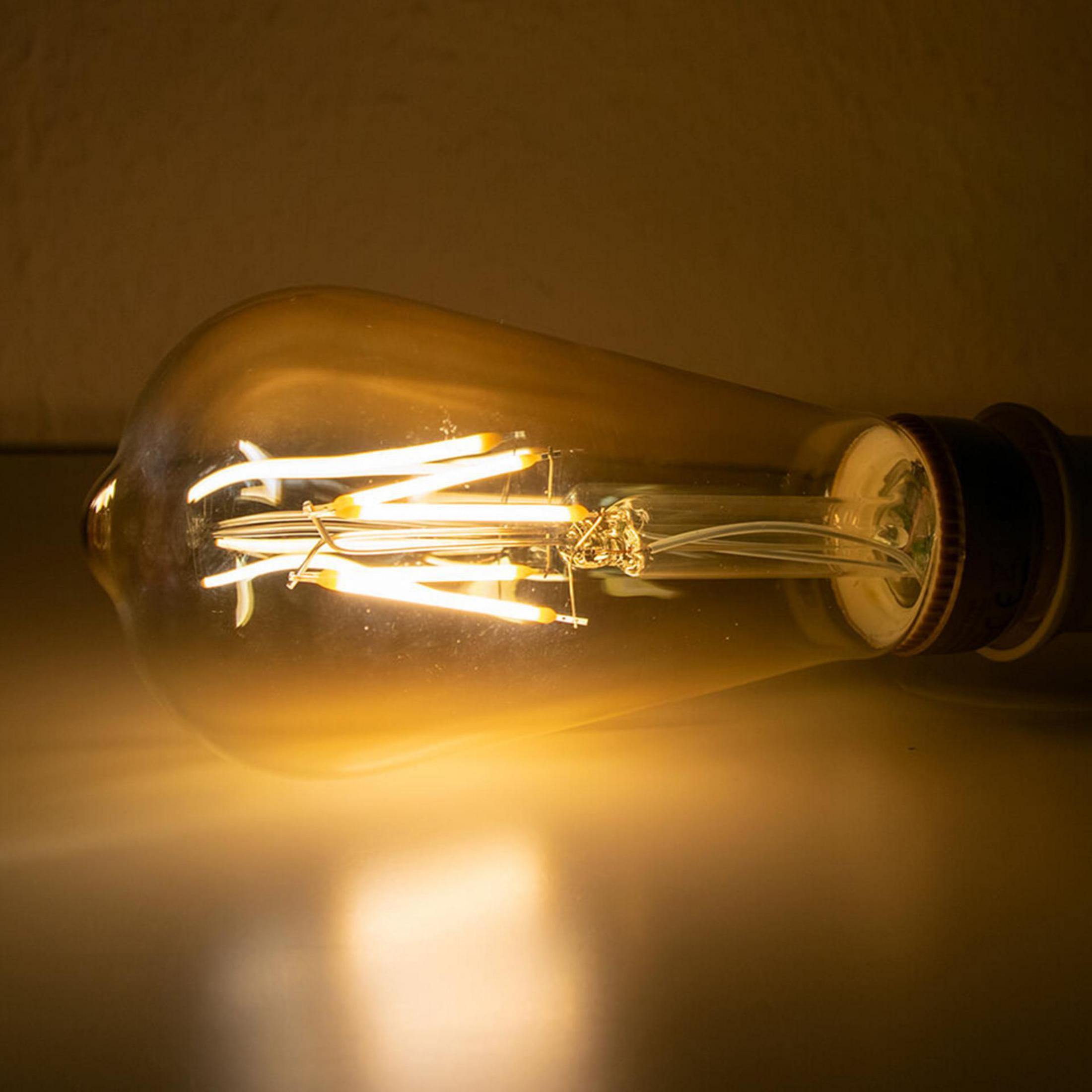 Nahaufnahme einer leuchtenden Edison-Glühbirne, die den glühenden Glühfaden auf dunklem Hintergrund zeigt.