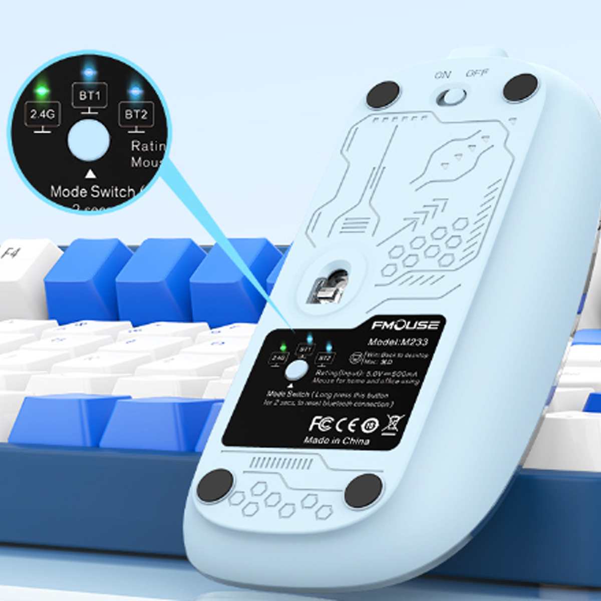 Hellblaue Maus auf Tastatur. Details auf der Unterseite, mit Modusschalter, FCC- und CE-Zeichen.