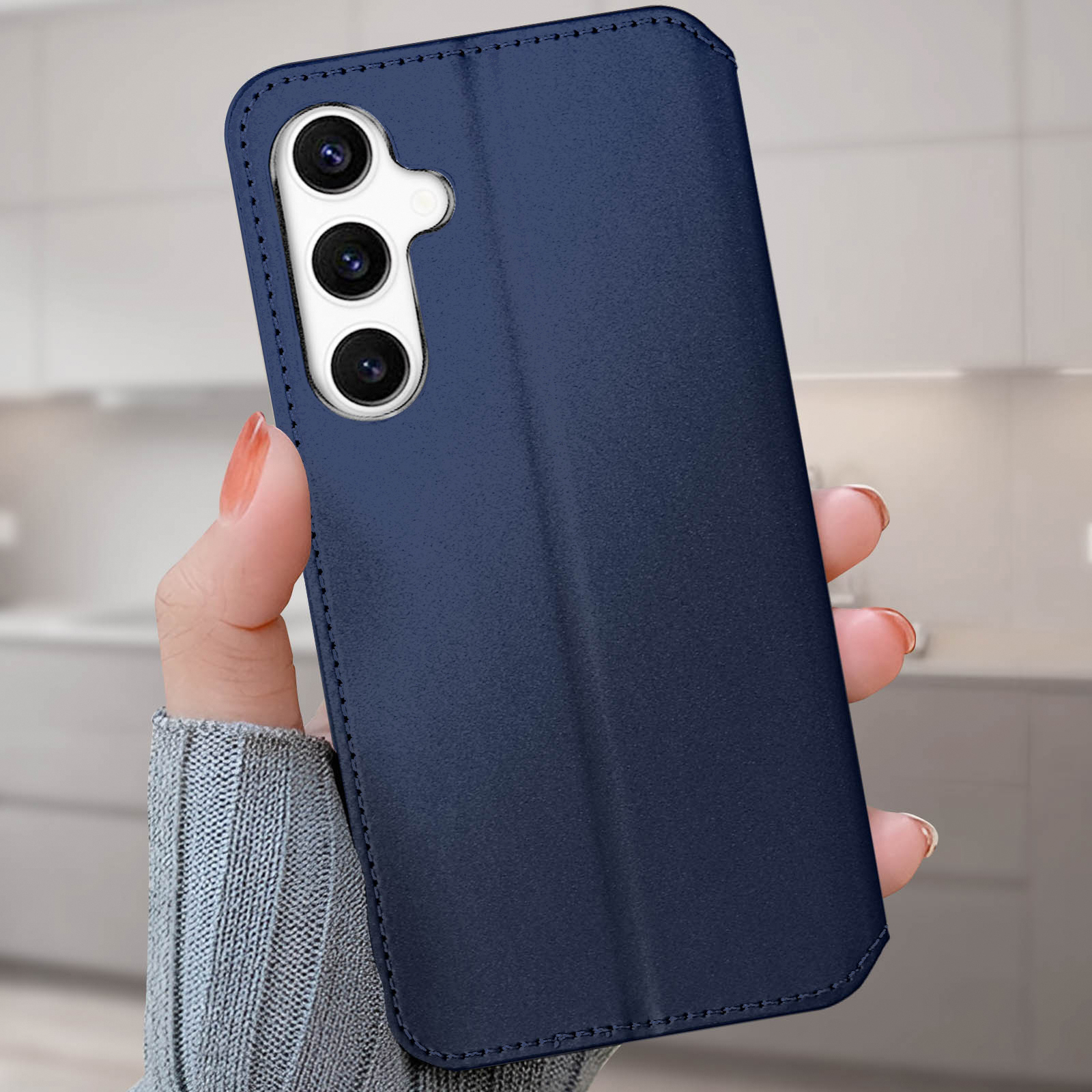 Mano che tiene una custodia per telefono in pelle blu chiusa.