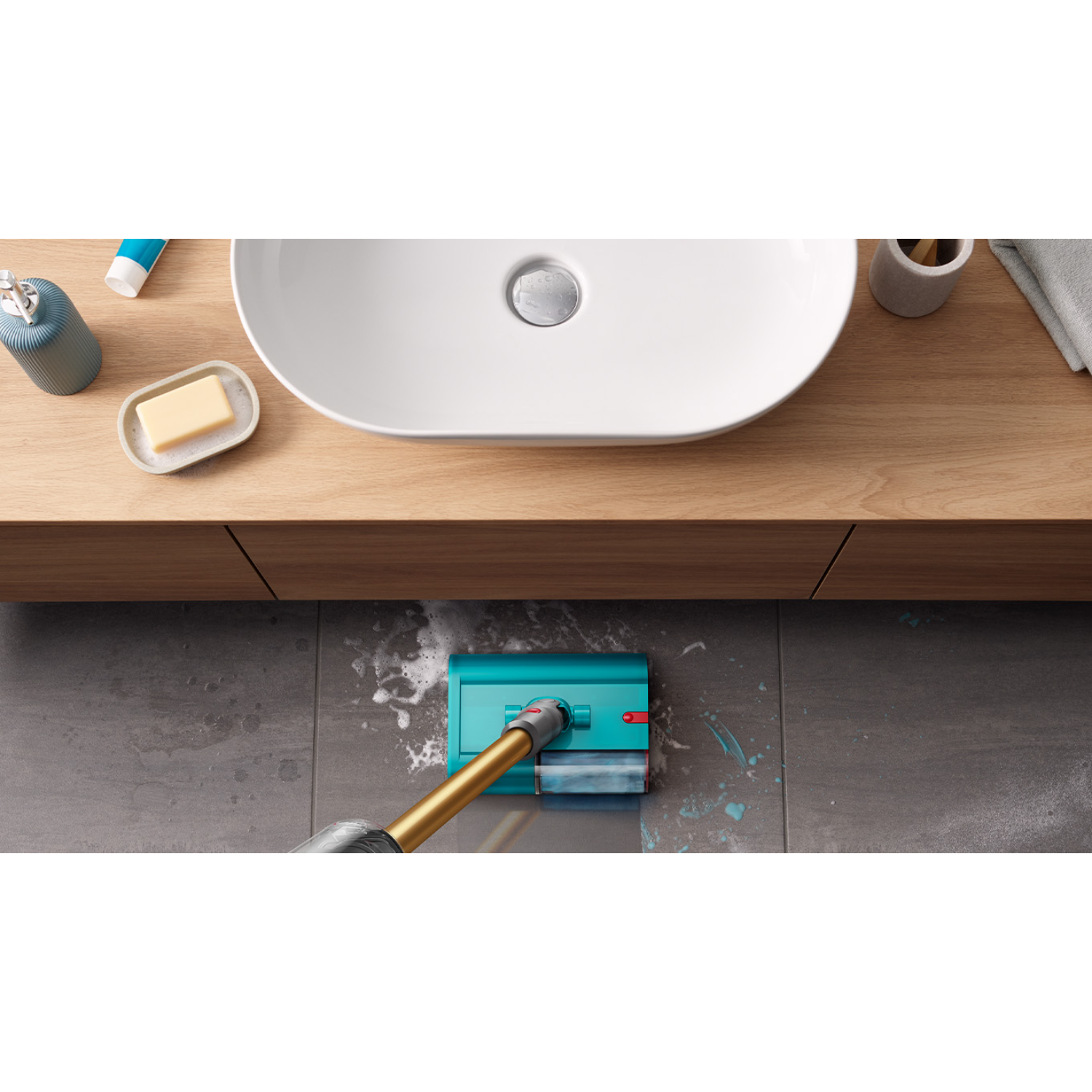 Un limpiador de pisos turquesa y dorado con un lavabo ovalado blanco y un mueble de madera en un baño.