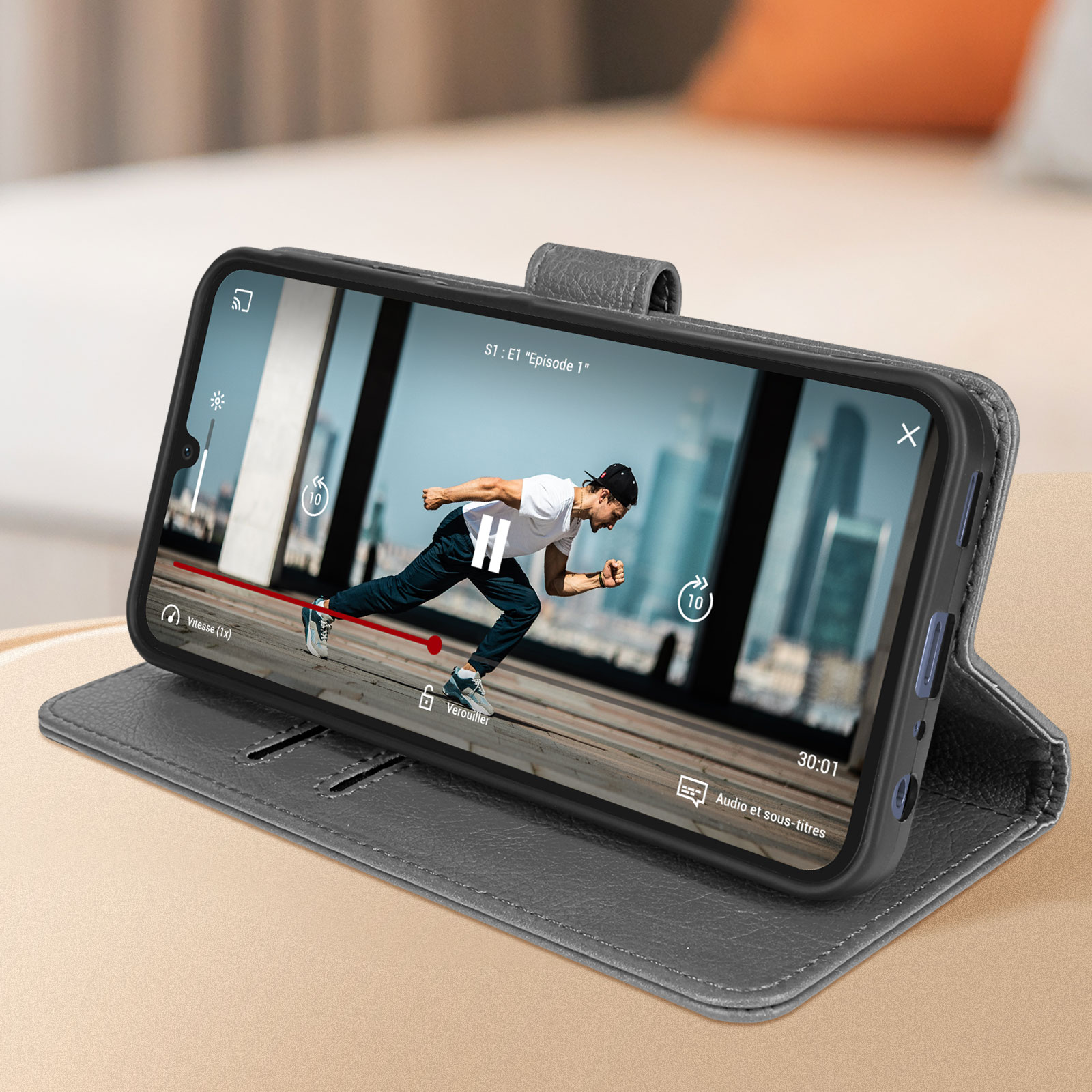 Ein Telefon in einer Hülle zeigt ein Video eines Mannes, der auf einem Holzboden rennt. Das Video hat Bedienelemente.