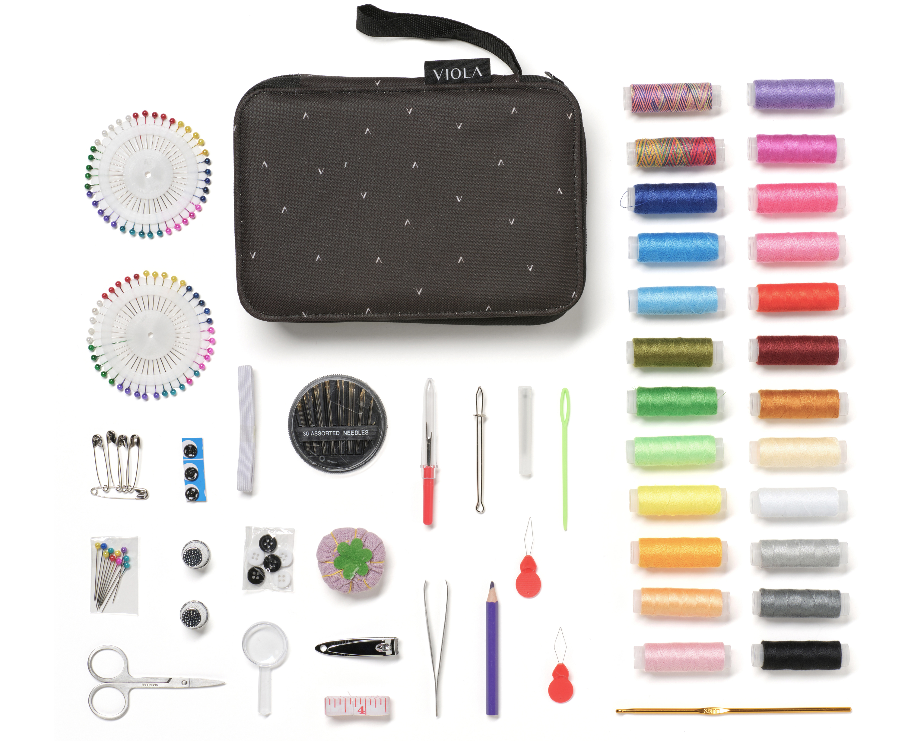 Contenido del kit de costura: hilos, agujas, tijeras, alfileres y otras herramientas, sobre blanco.