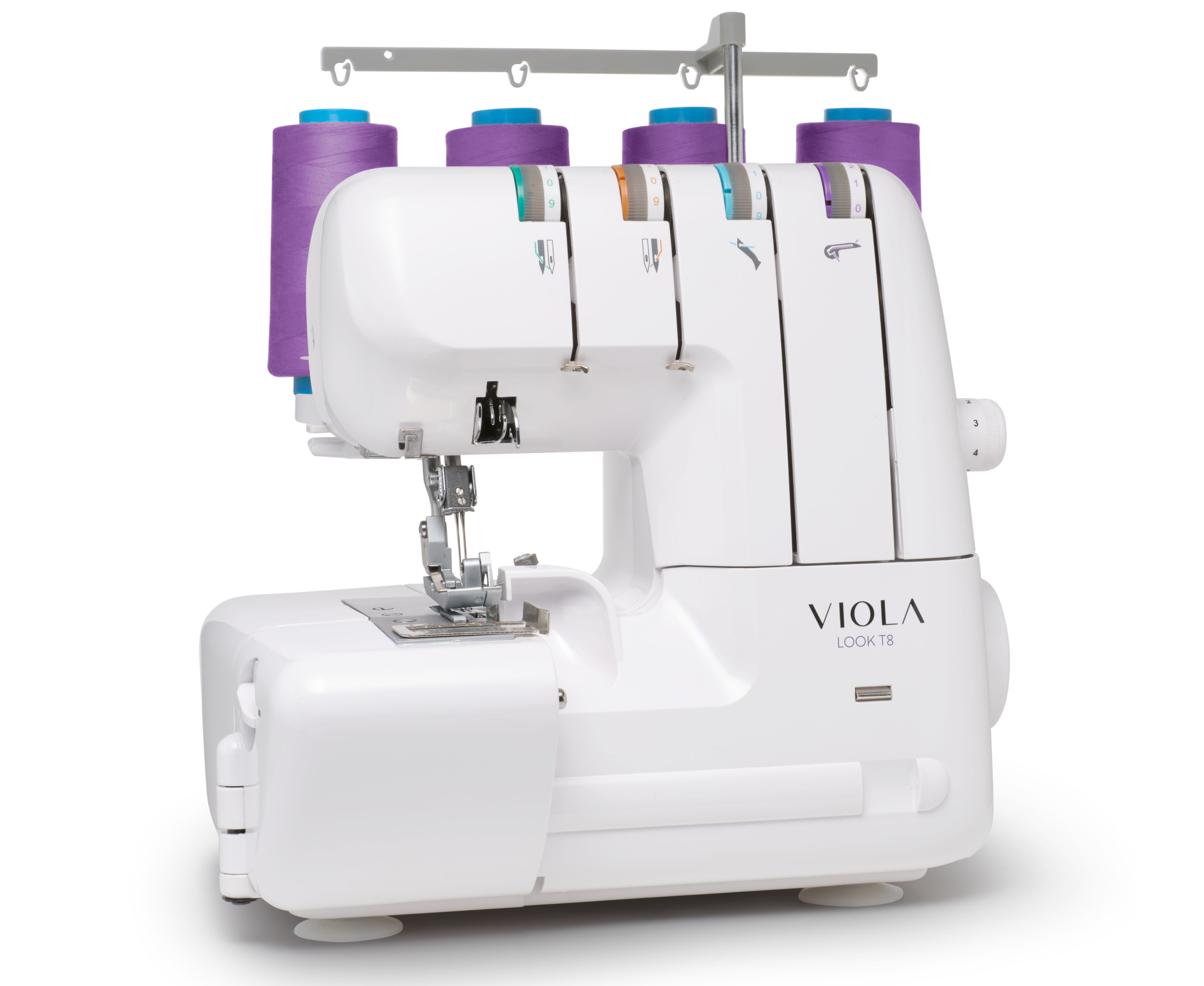 Una máquina de coser blanca con carretes de hilo morado encima, vista desde un ángulo bajo sobre un fondo blanco.