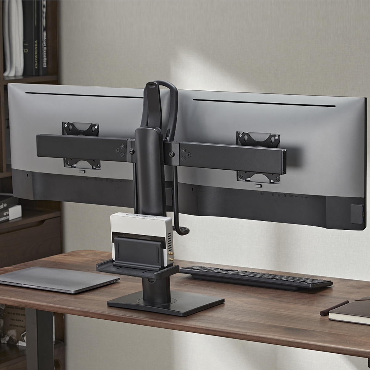 Doppel-Monitorständer, zwei Monitore, ein Laptop, eine Tastatur und andere Schreibtischartikel.