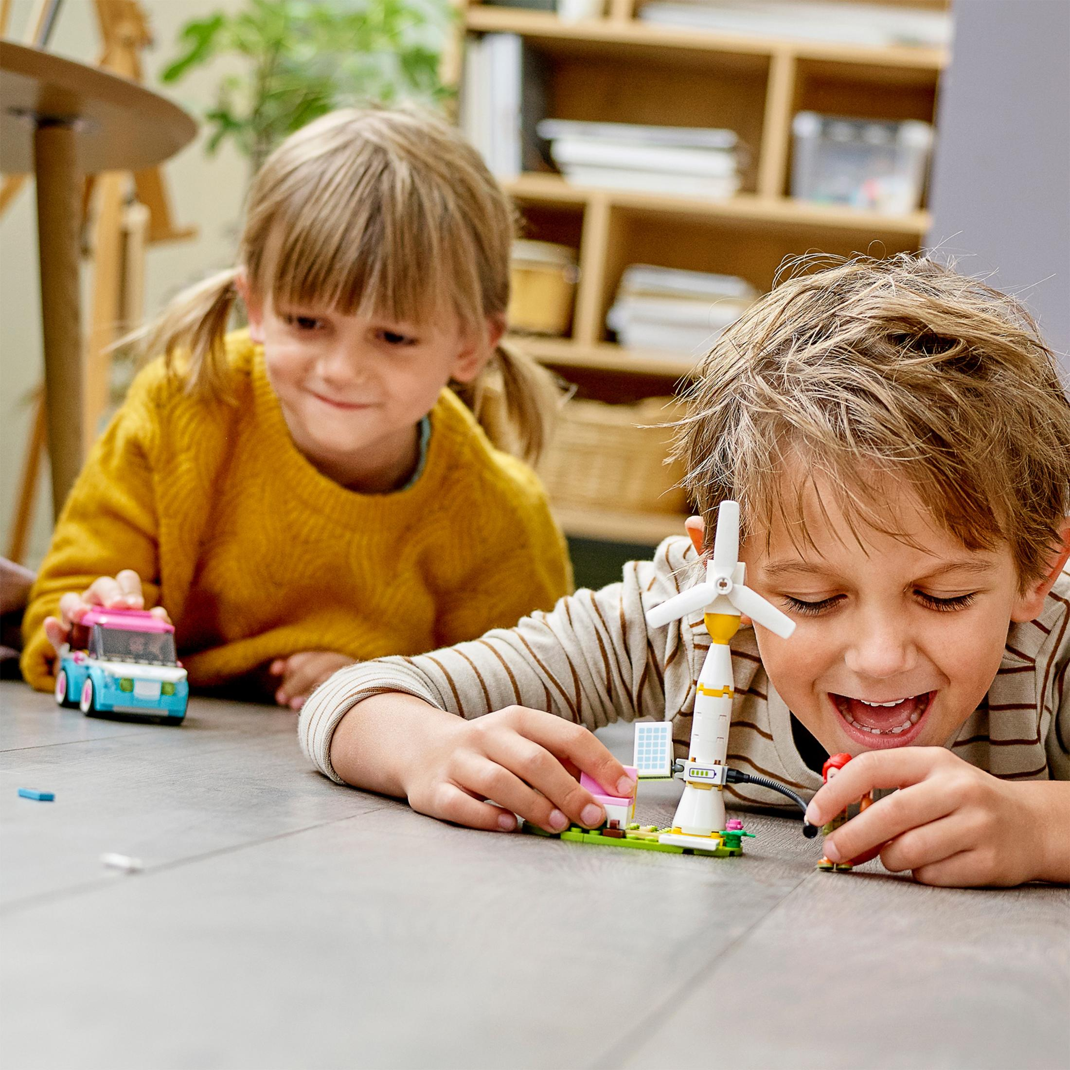 Zwei Kinder spielen mit Lego, eines mit einer Windmühle und das andere mit einem Spielzeugauto.