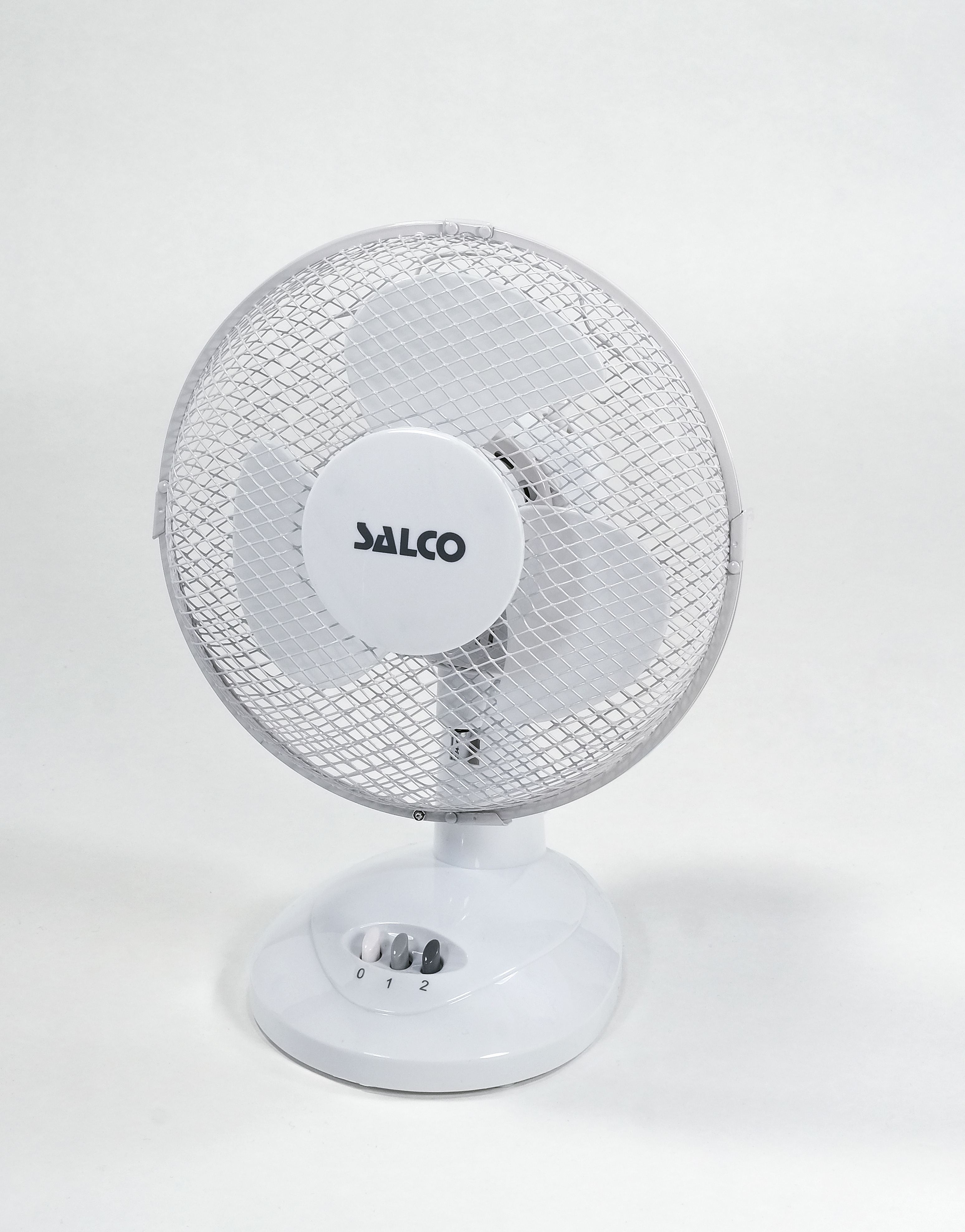 Weißer elektrischer Ventilator auf weißer Oberfläche. Der Ventilator hat ein silbernes Gitter und einen weißen Sockel.