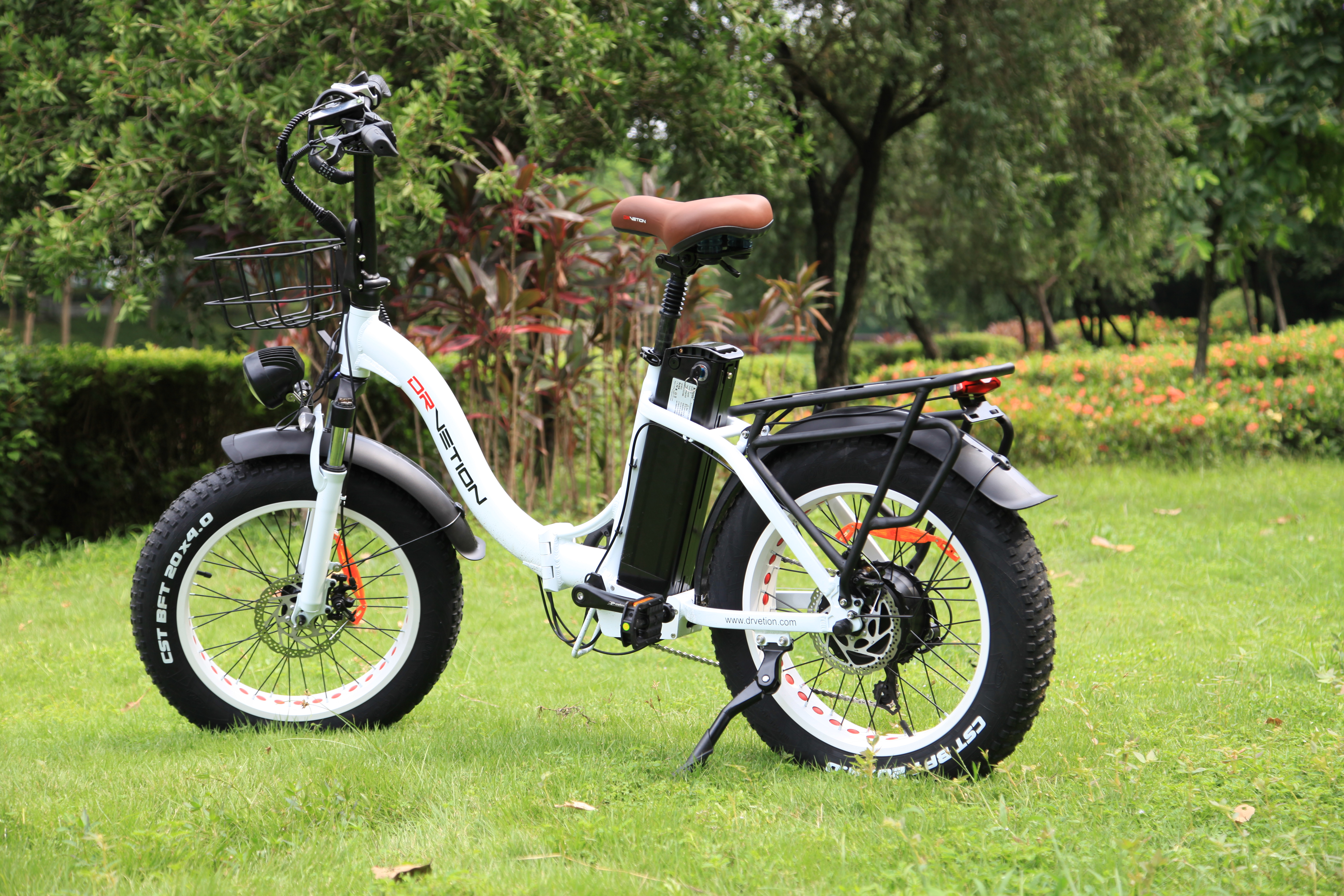 Weißes Elektrofahrrad mit schwarzen Akzenten auf Gras. Im Hintergrund ein grüner Park.