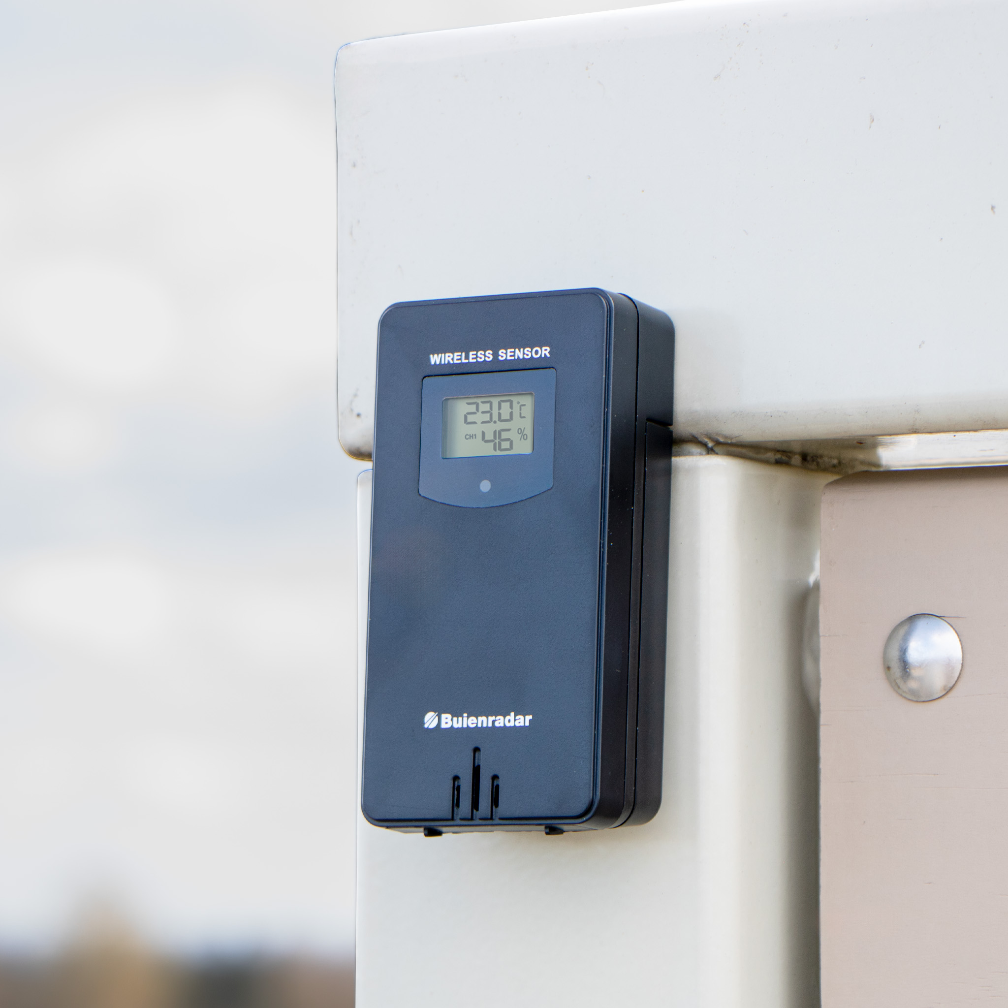 Schwarzer drahtloser Wettersensor auf beiger Oberfläche. Weißer Hintergrund.