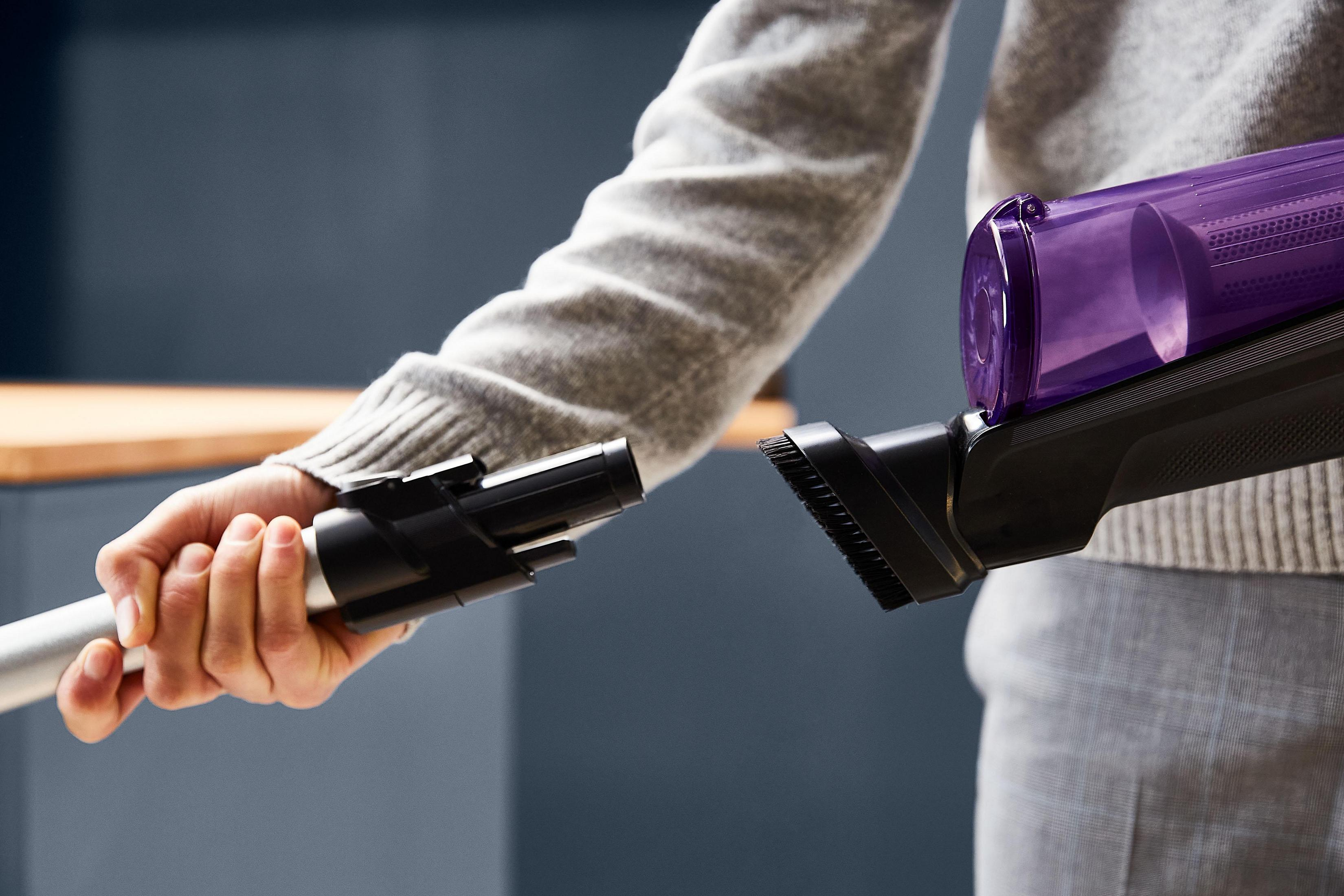 Le mani di una persona che collega gli accessori a un aspirapolvere.