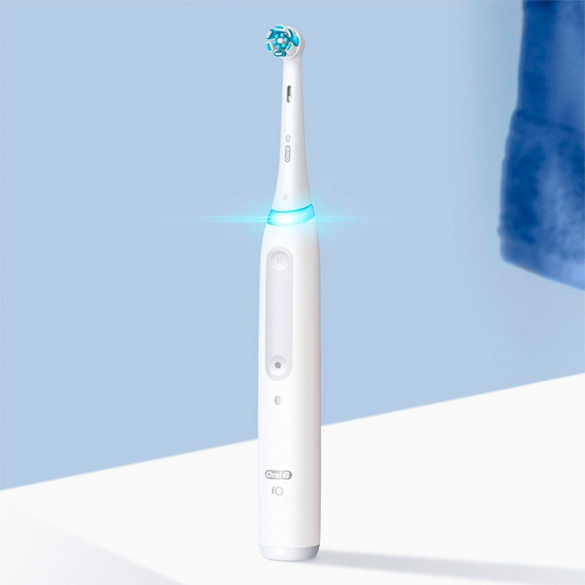 Un cepillo de dientes eléctrico blanco con una luz azul en la cabeza, contra un fondo azul claro.