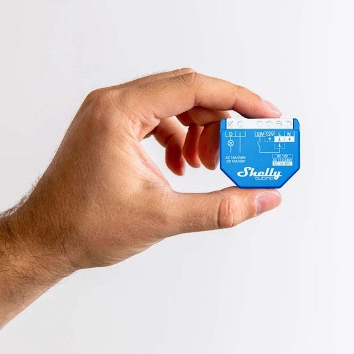 Eine Hand, die ein blaues Smart-Home-Gerät hält. Das Gerät hat Beschriftungen und Anschlusspunkte.
