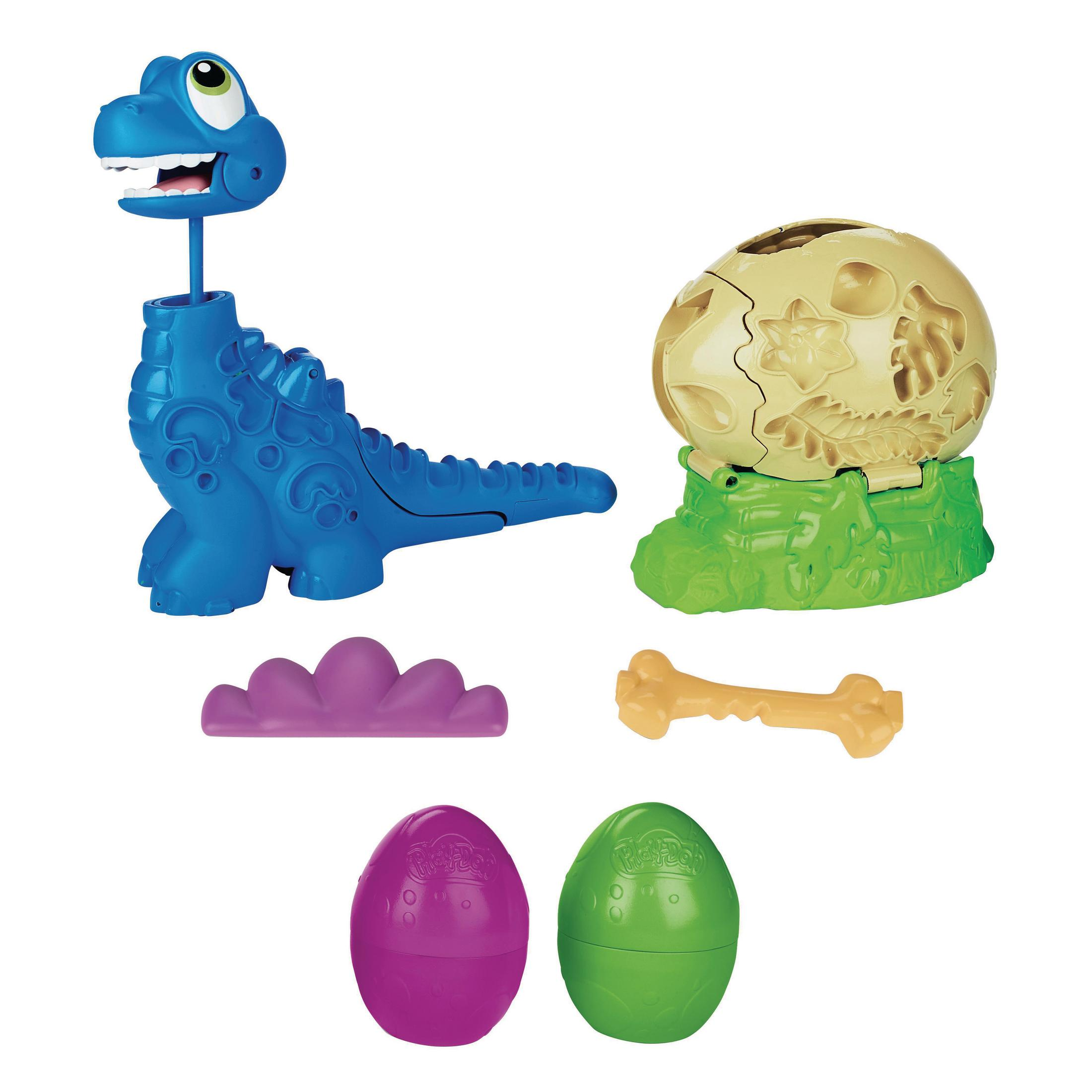 Un juguete de dinosaurio azul con la boca abierta, una base verde, dos huevos de Play-Doh y un hueso.
