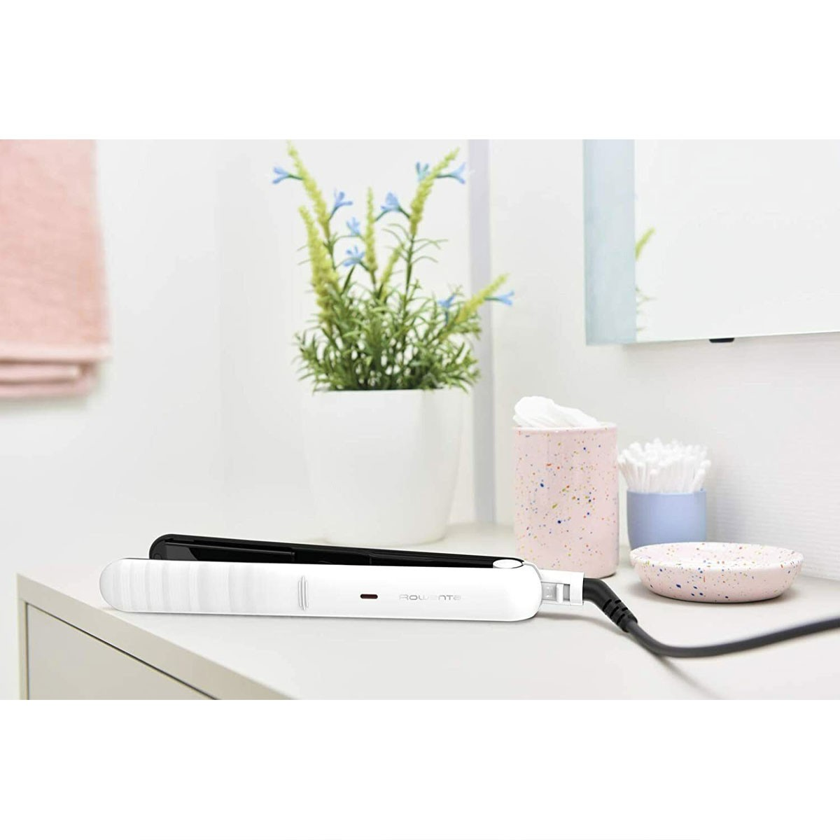 Plancha de pelo blanca y negra sobre superficie blanca. Accesorios al lado.