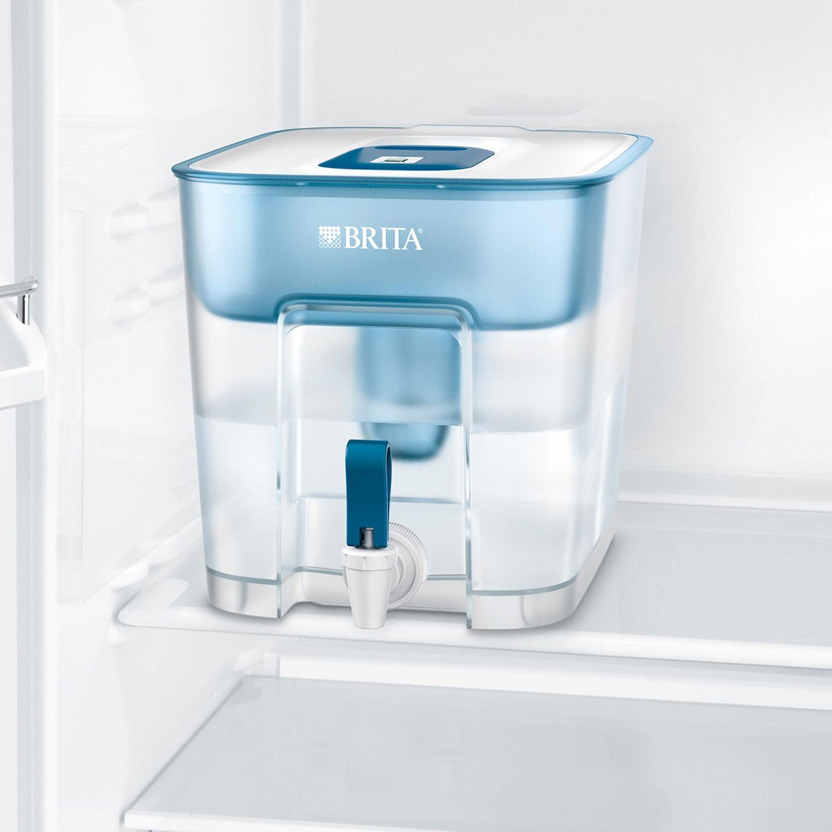Weiß-blauer Wasserfilter-Krug in einem Kühlschrank. Der Krug hat einen Wasserhahn und einen Deckel.