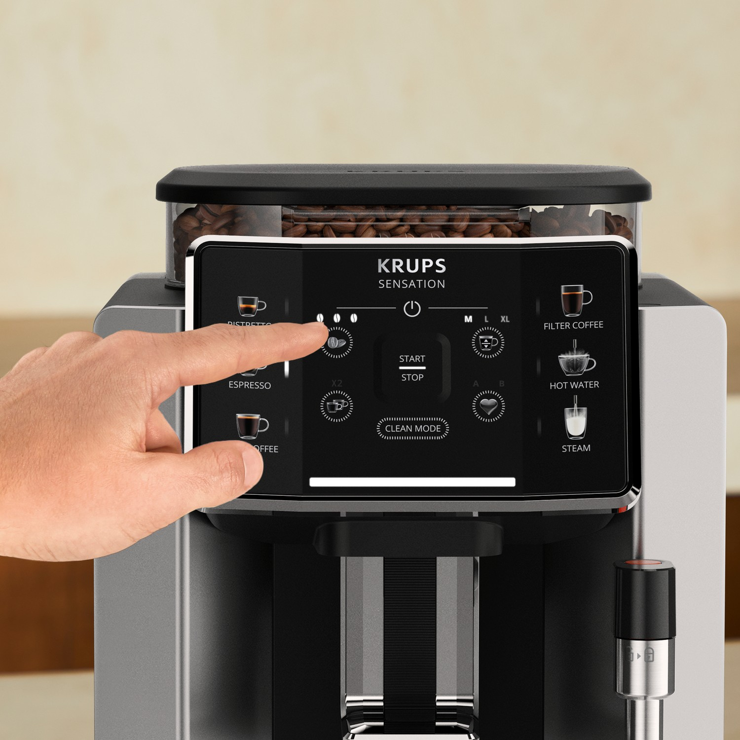 Ręka naciska przycisk na ekspresie do kawy Krups Sensations. Maszyna jest srebrna.