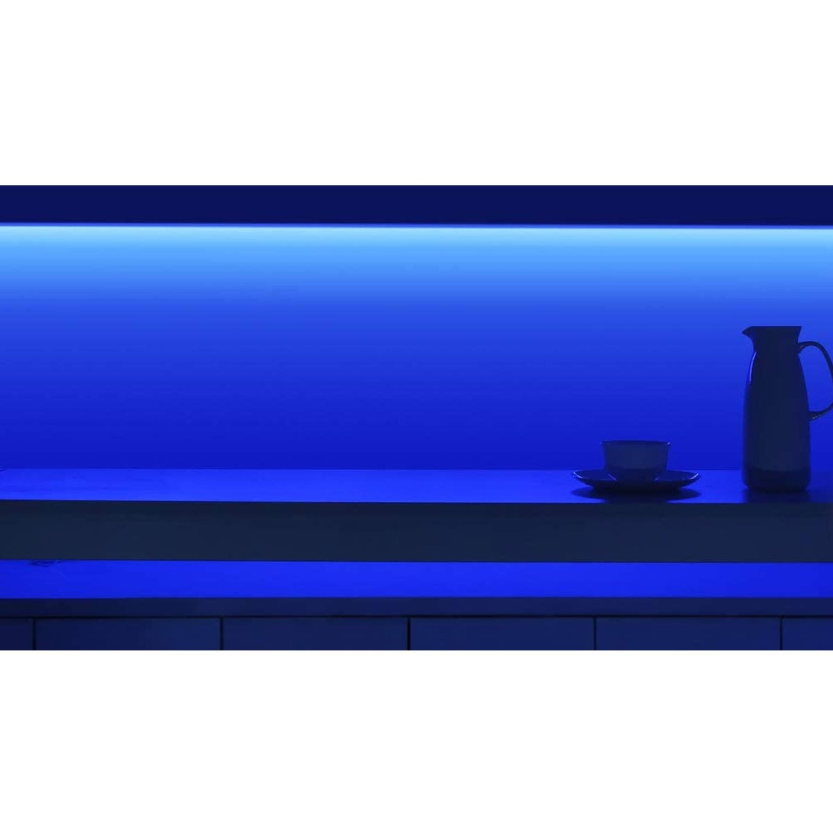 Una mensola illuminata di blu con tazza, brocca e sfondo azzurro.