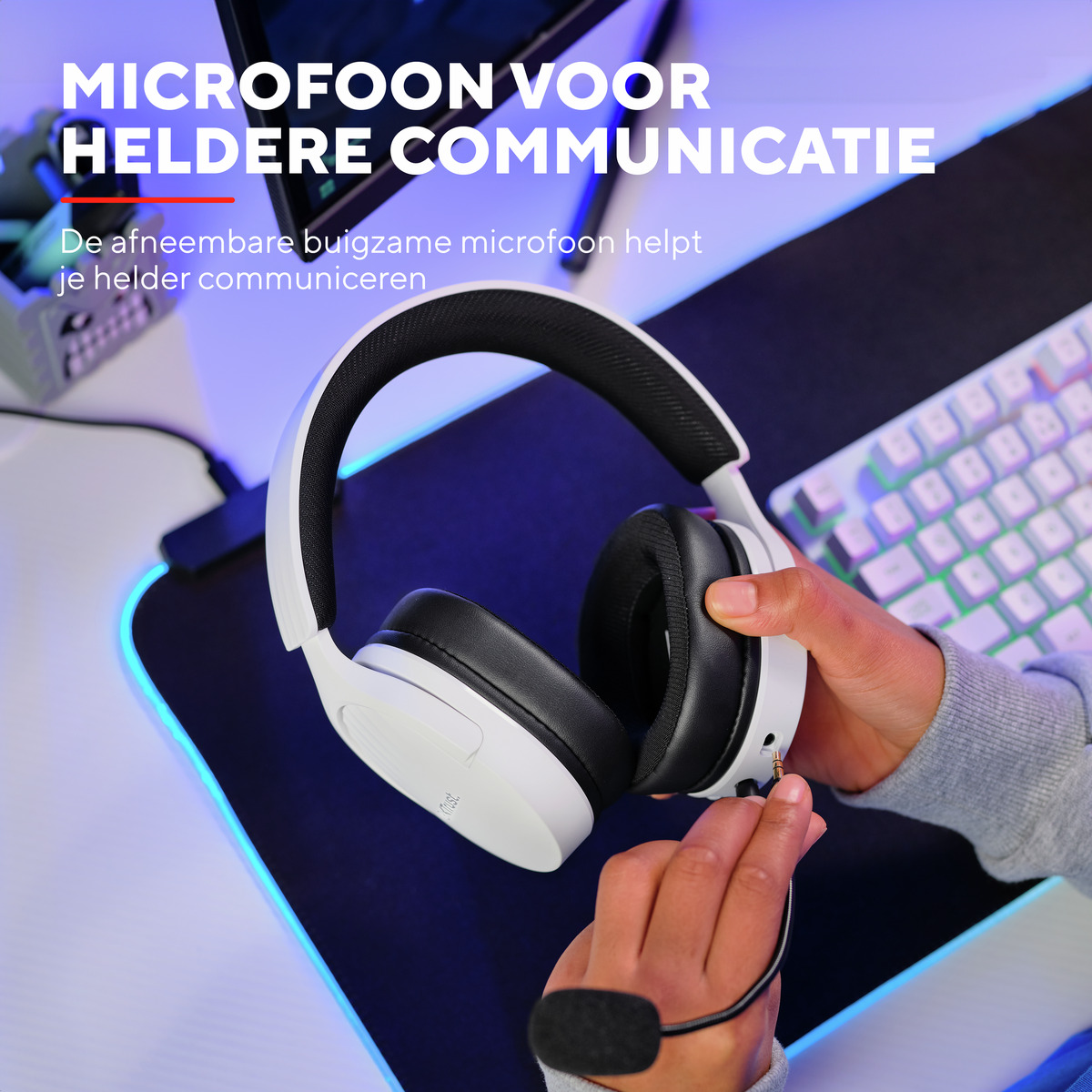 Osoba trzymająca białe słuchawki z mikrofonem przed klawiaturą.