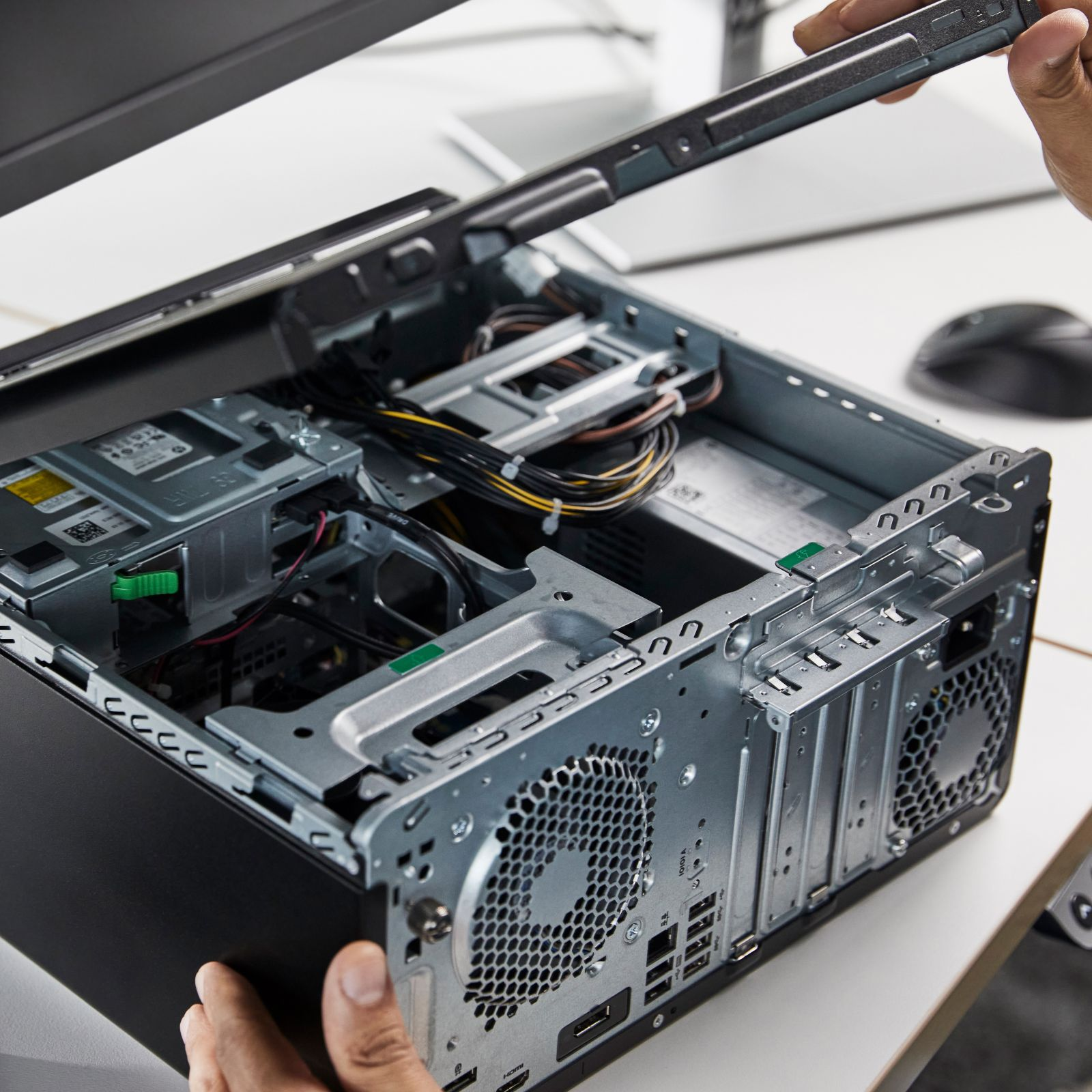 Hände, die einen Computer zusammenbauen. Das Gehäuse ist geöffnet und gibt die Innenteile frei.