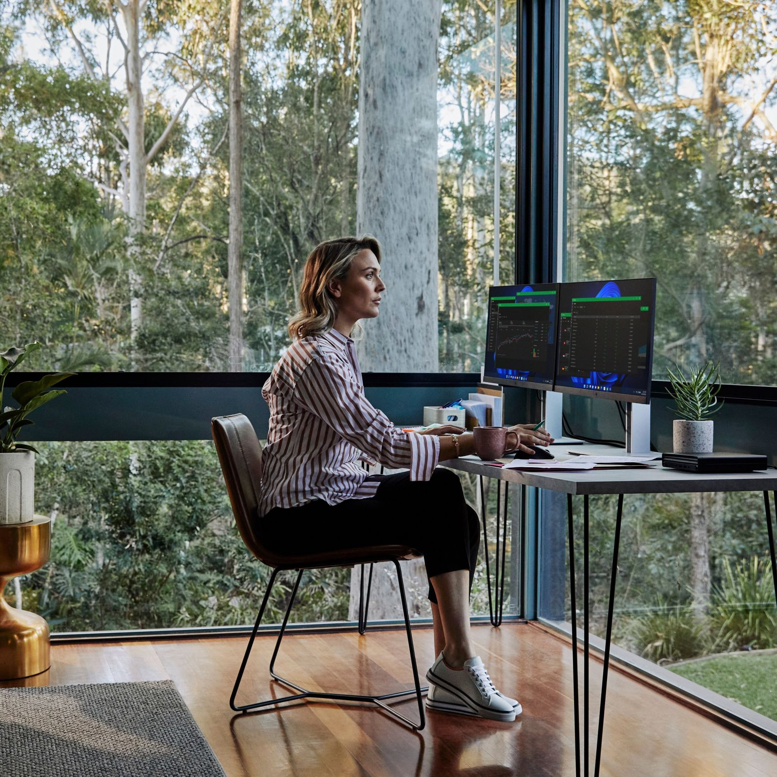 Donna che lavora al computer vicino a una finestra con vista su una foresta.