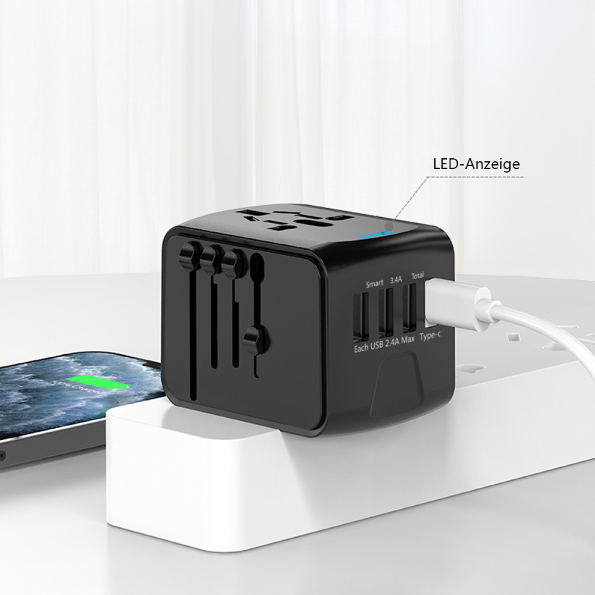 Schwarzer Multiport-Adapter auf weißer Oberfläche, lädt ein Telefon. Blaue LED leuchtet.