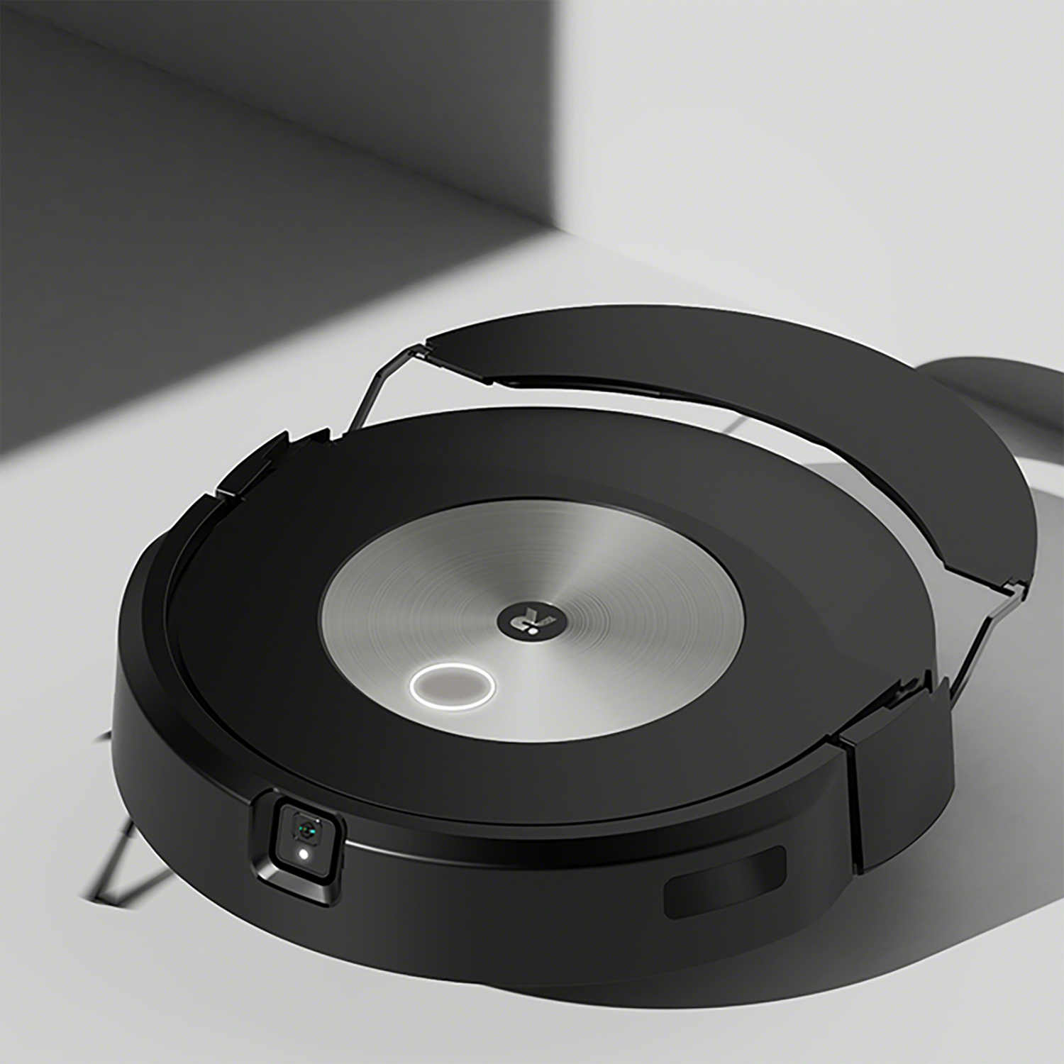 Czarny odkurzacz automatyczny na białej powierzchni. Ma okrągły kształt i uchwyt.