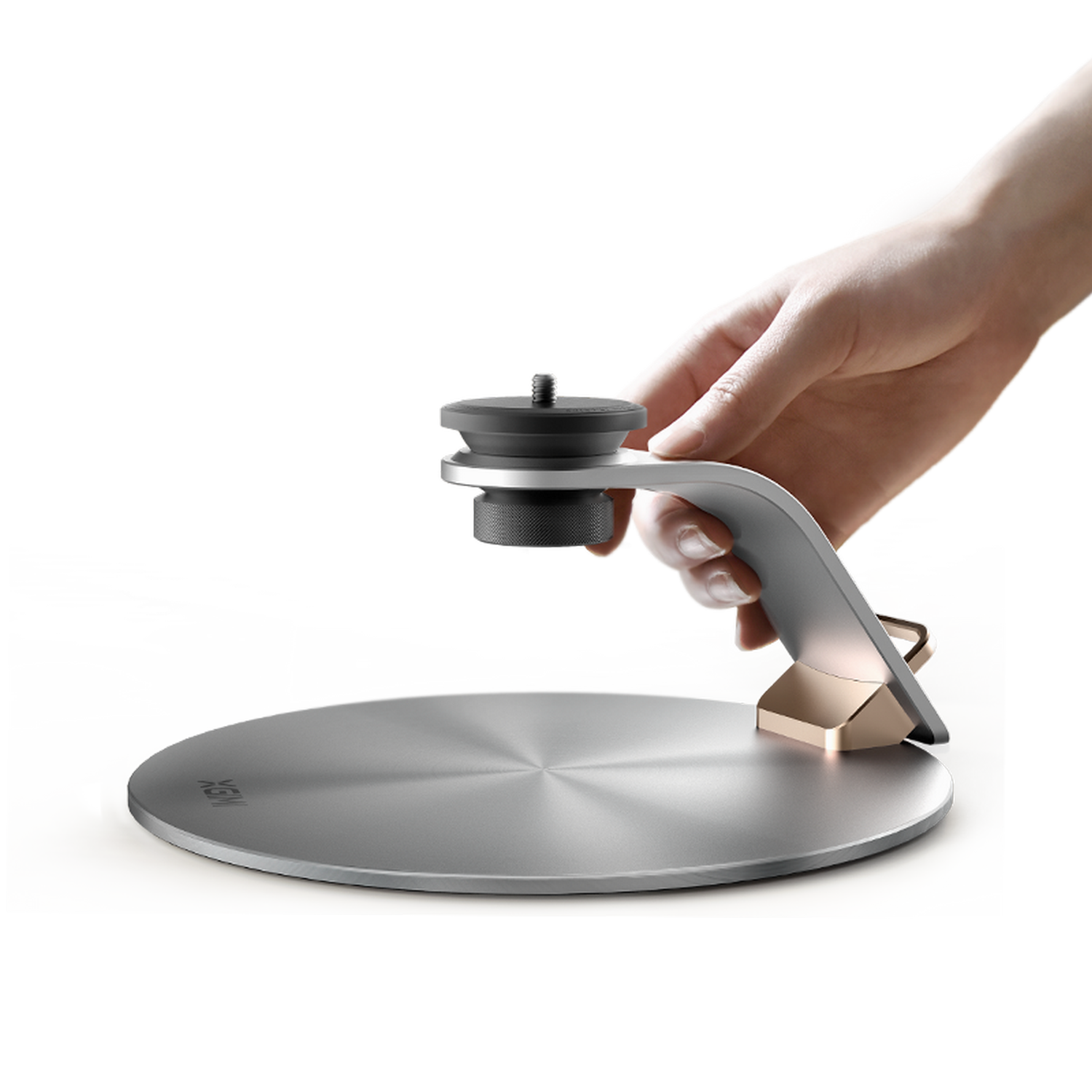 Srebrny i złoty stojak trzymający urządzenie. Dłoń trzyma go nad metalową podstawą.