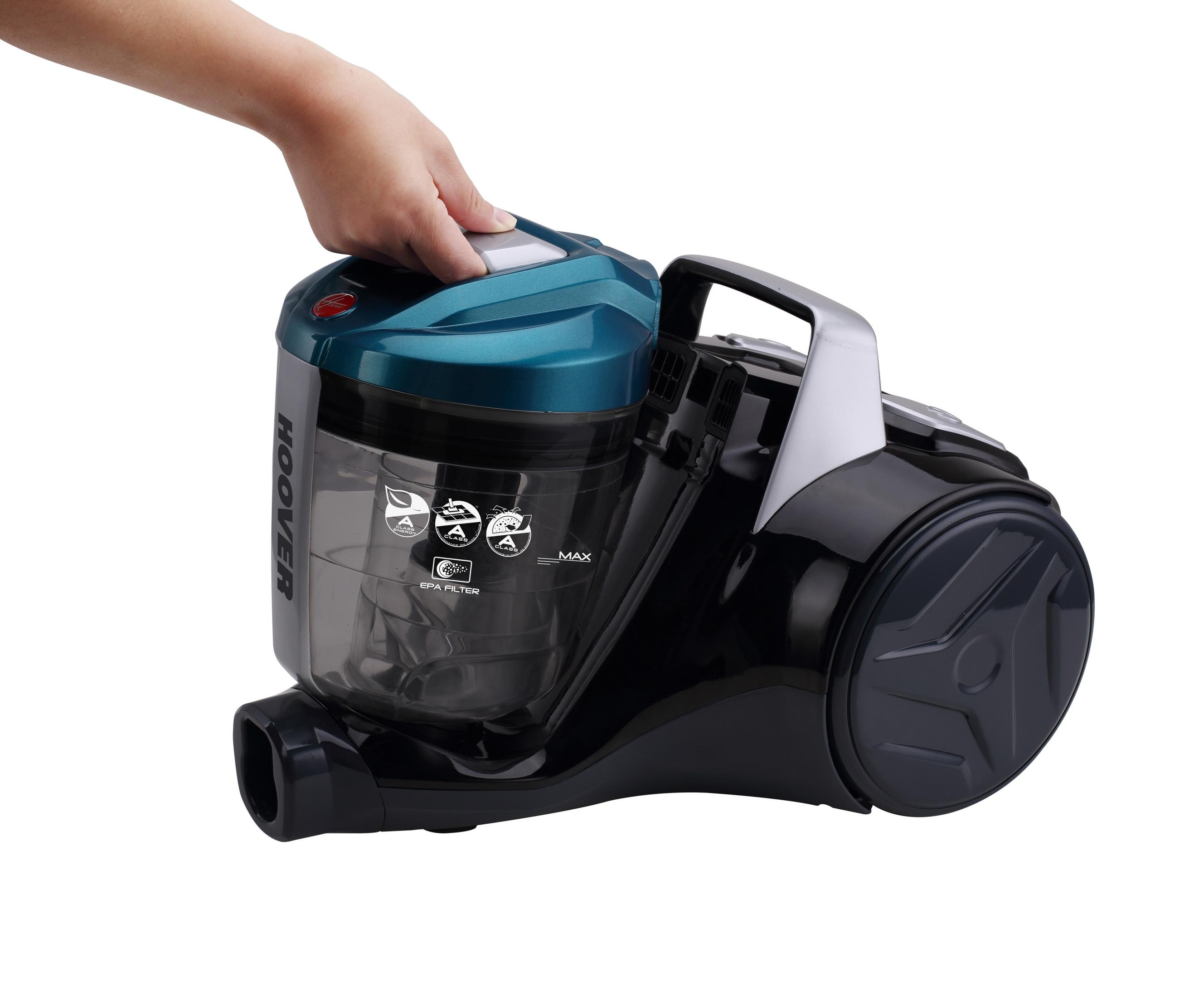 Ręka trzymająca turkusowo-czarny odkurzacz z przezroczystym pojemnikiem na kurz.