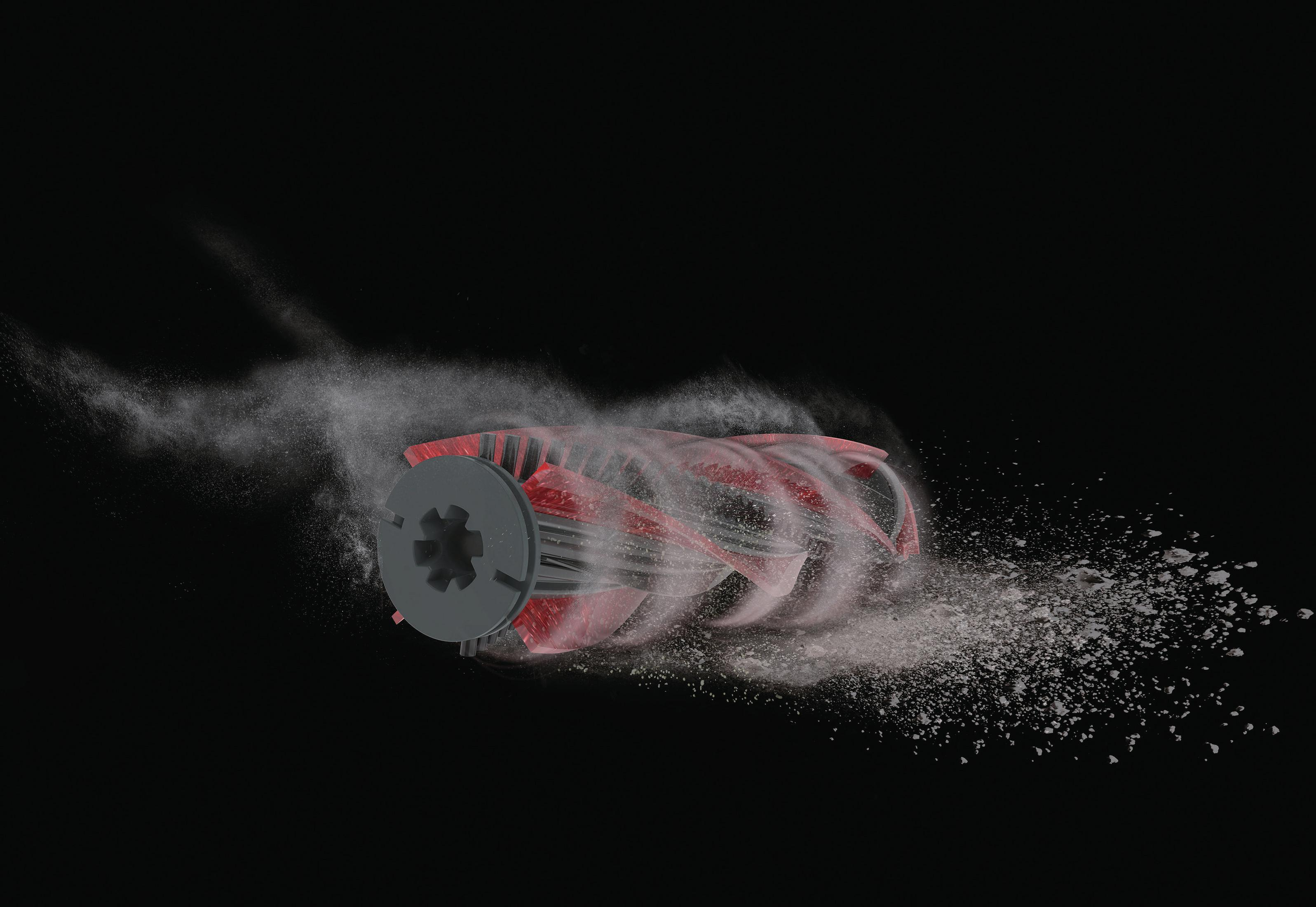 Czerwono-szara szczotka do odkurzacza, otoczona cząsteczkami kurzu na czarnym tle.