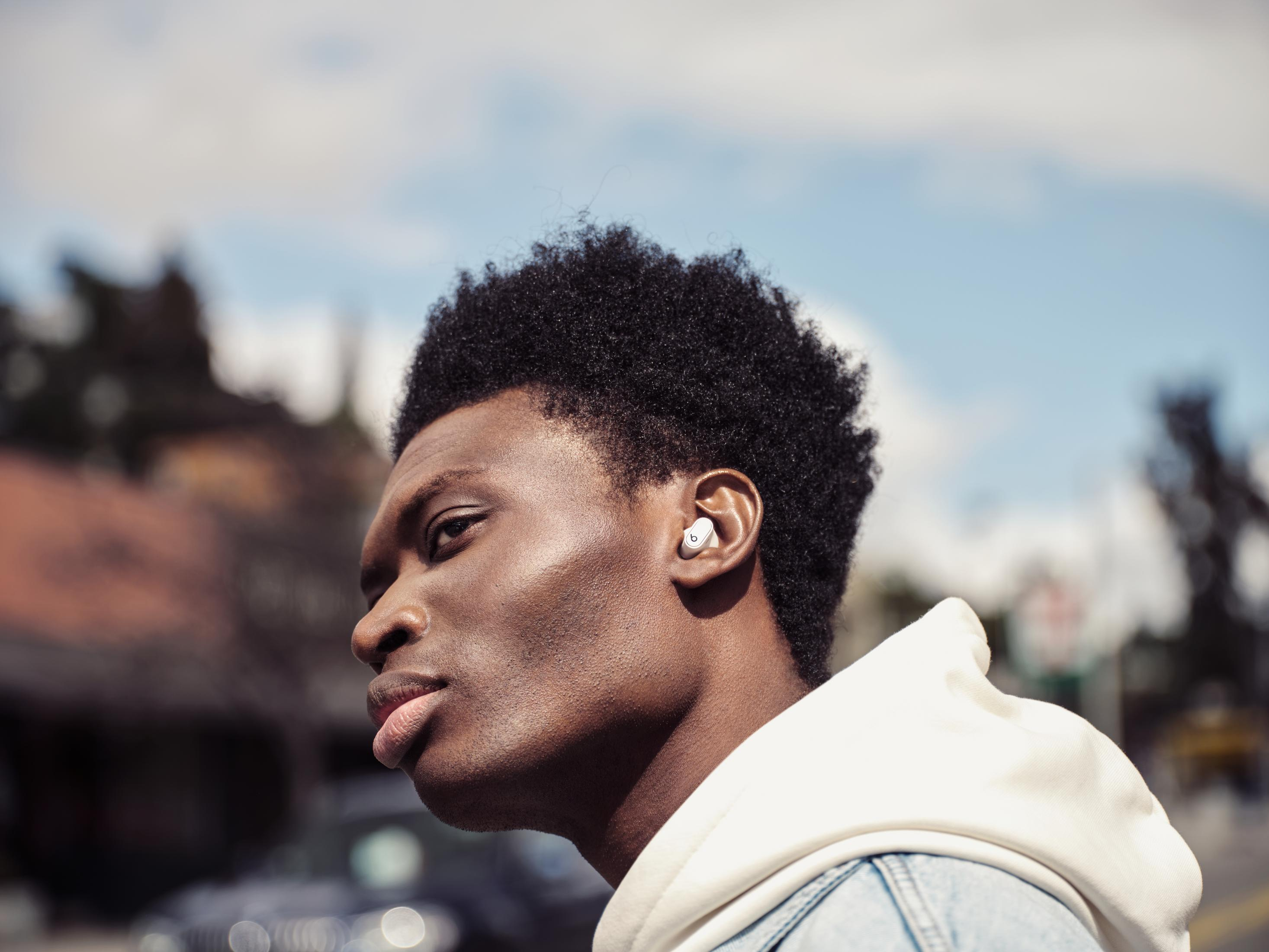 Mężczyzna ze słuchawkami w uchu, odwrócony, z tłem miejskim.