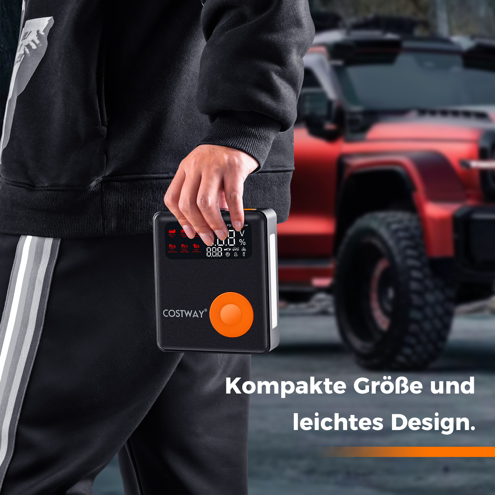 Eine Person hält einen schwarz-orangenen tragbaren Luftkompressor, rotes SUV im Hintergrund.