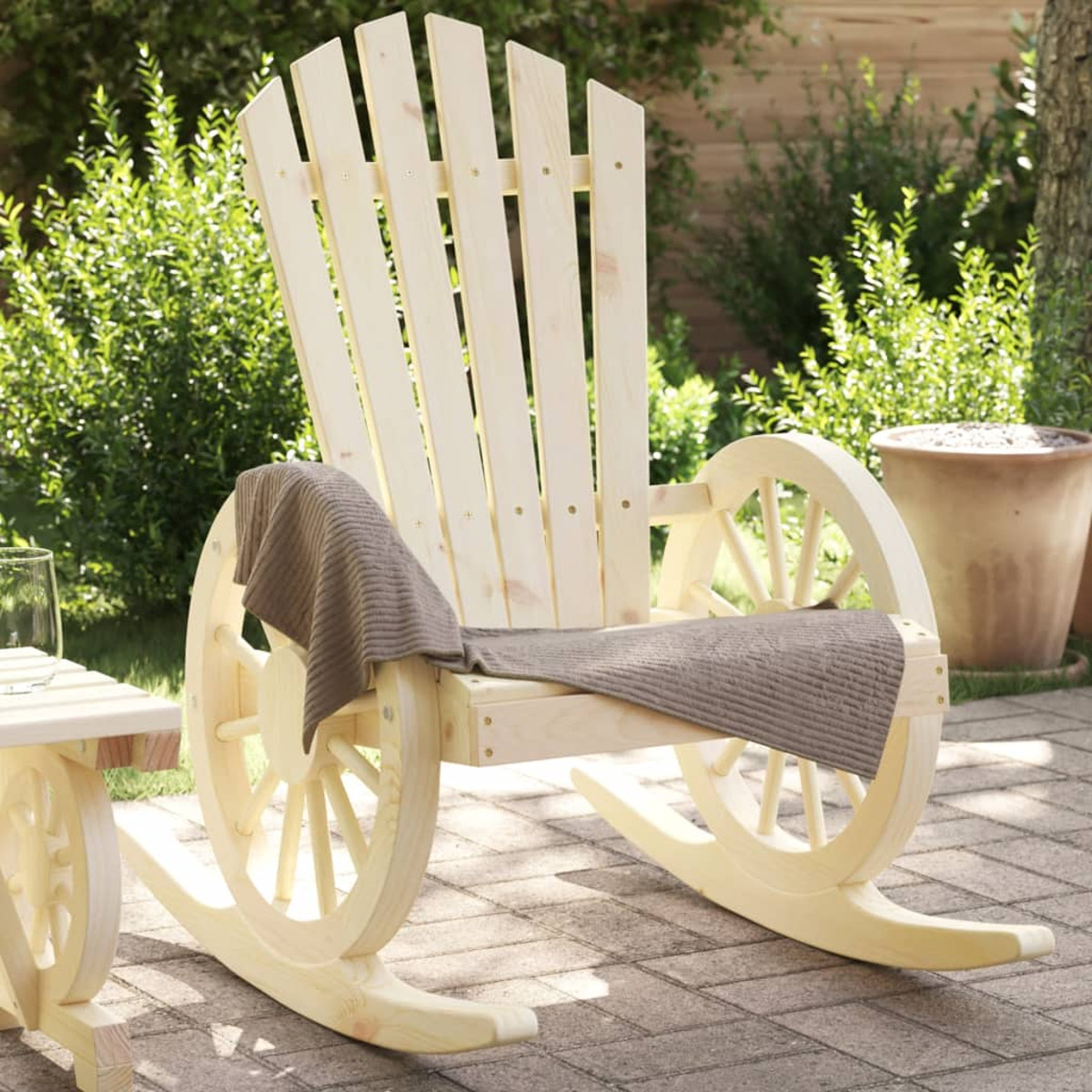 Schaukelstuhl aus Holz mit Wagenradseiten. Ein Handtuch ist über dem Sitz drapiert. Ziegelterrasse.