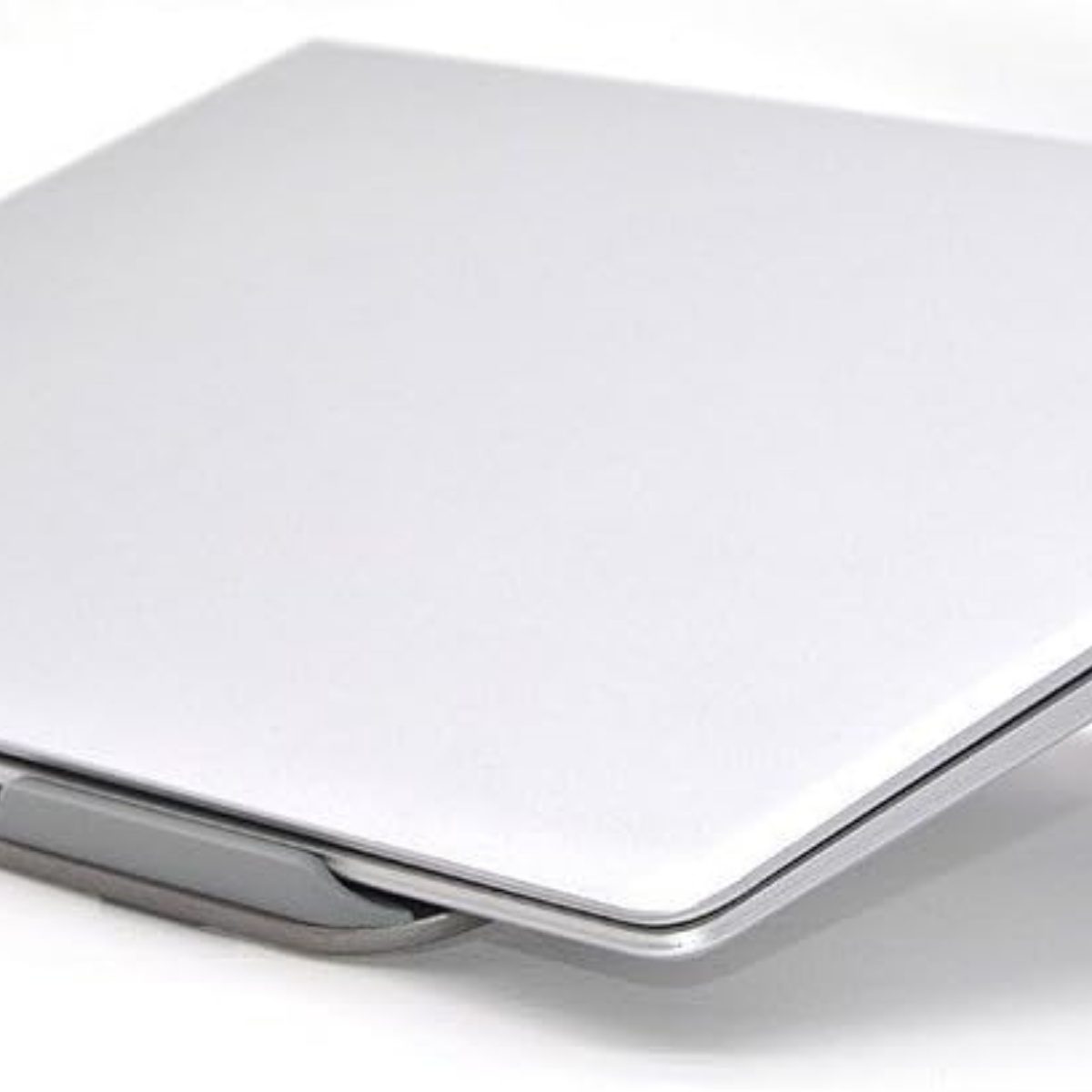 Nahaufnahme eines silbernen Laptops, leicht geöffnet, auf weißer Oberfläche.