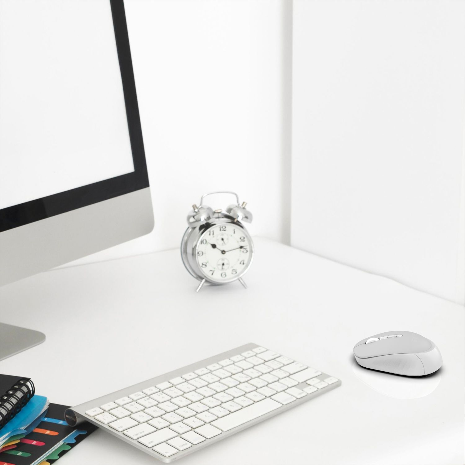 White desk with a computer, alarm clock, keyboard, and mouse.