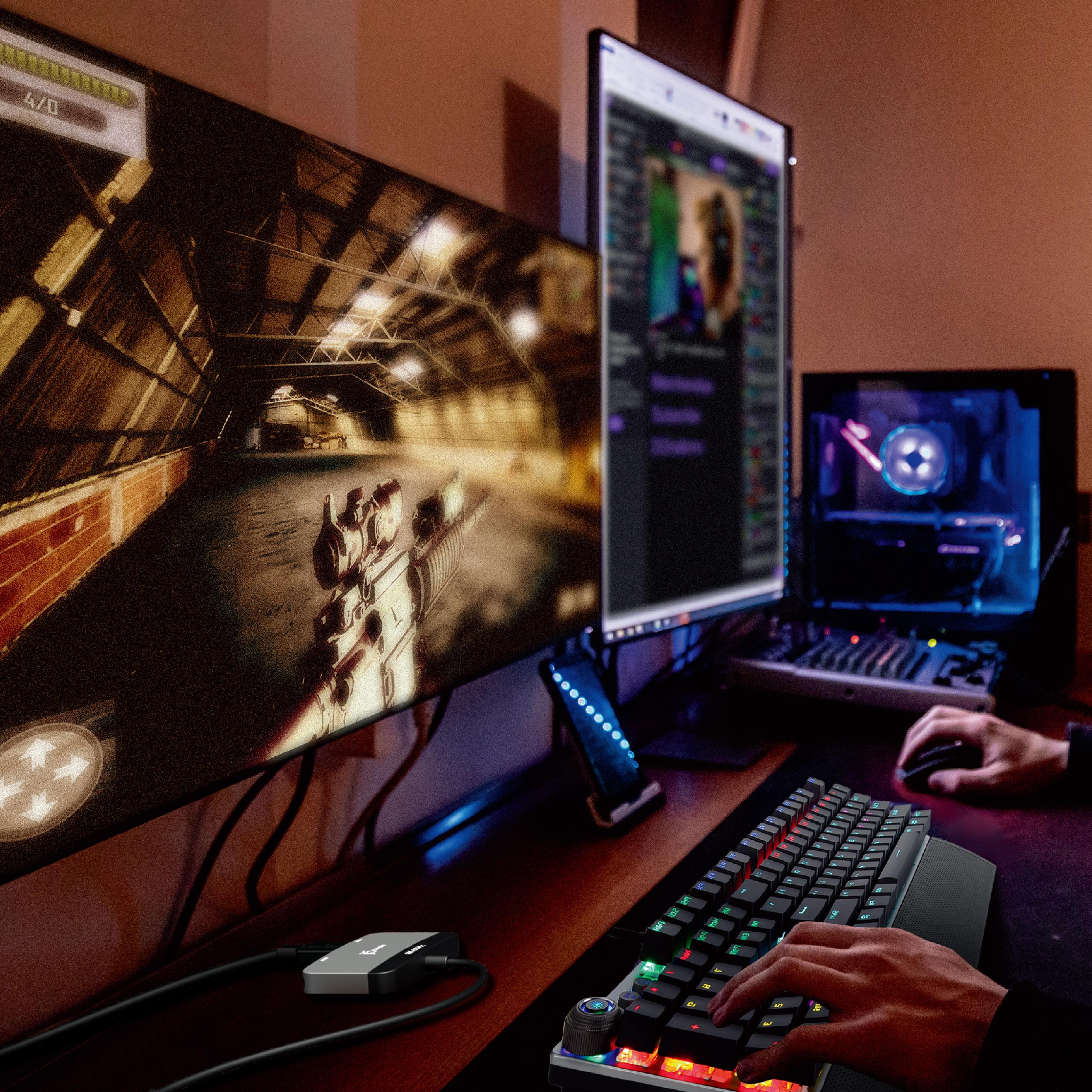 Gaming-Setup mit mehreren Monitoren, Tastatur und Maus, beleuchteter Raum.