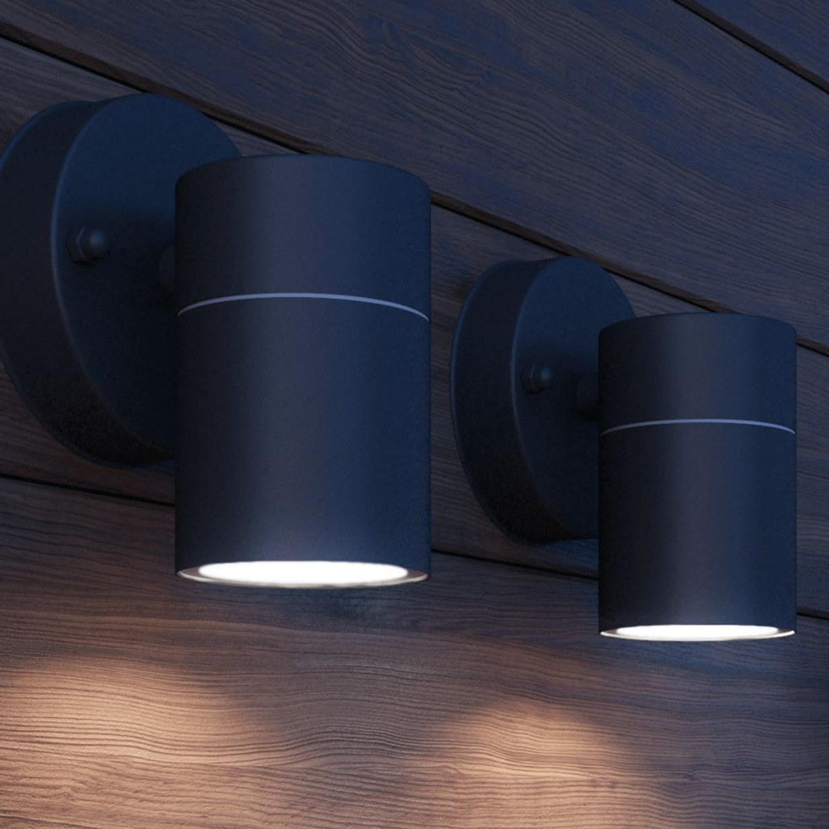 Zwei schwarze zylindrische Wandleuchten an Holzpaneelen. Das Licht ist an.