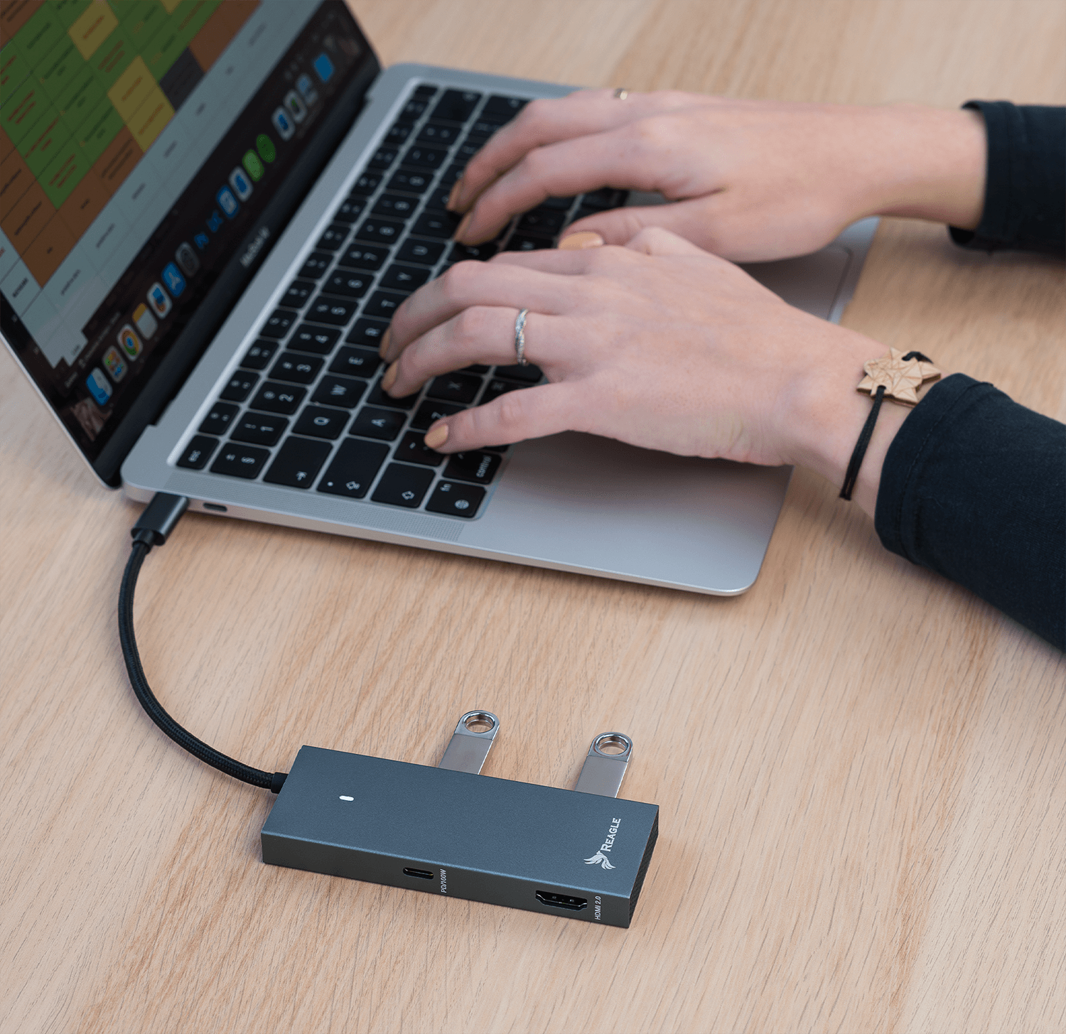 Laptop z hubem USB i dwoma podłączonymi dyskami USB, ręce piszące na klawiaturze.