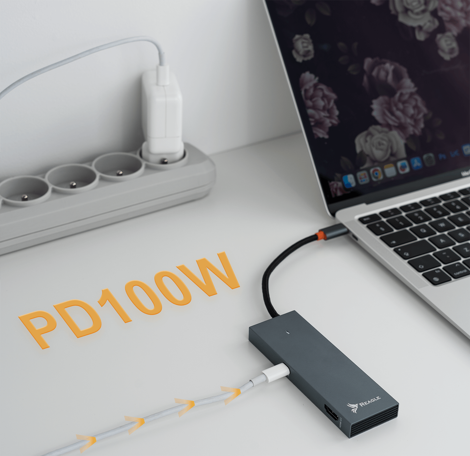 Laptop z zasilaczem i podłączonym hubem USB-C. Słowa PD100W są w pomarańczowym tekście.