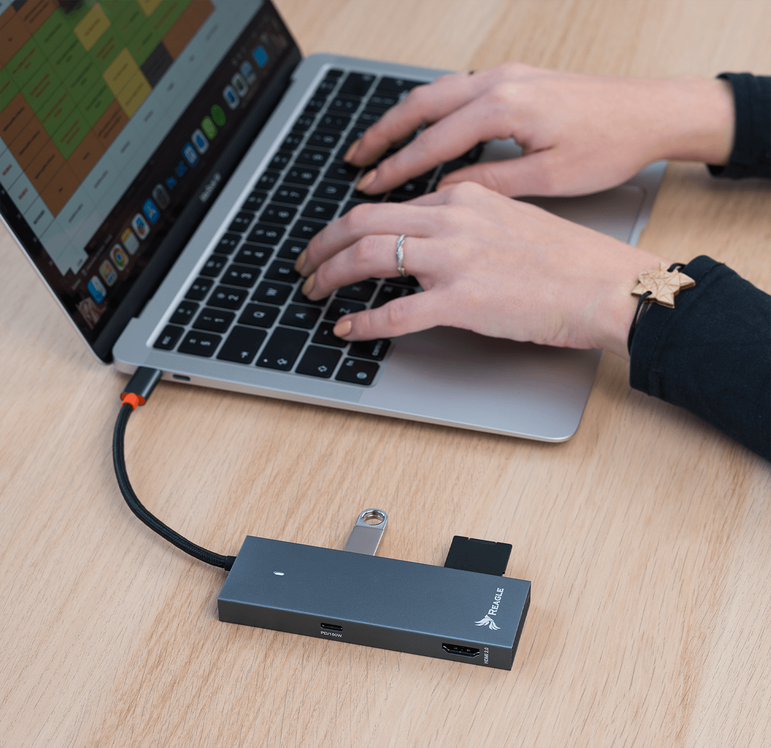 Ręce piszące na klawiaturze laptopa, z hubem i dyskiem USB.