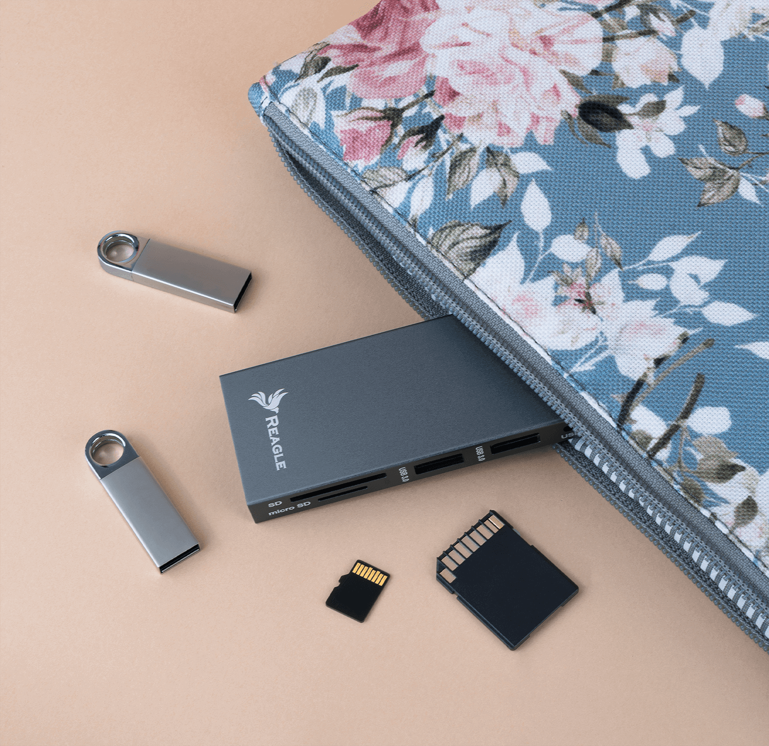 Etui z akcesoriami takimi jak pendrive'y, karty SD i Micro SD, na beżowej powierzchni.