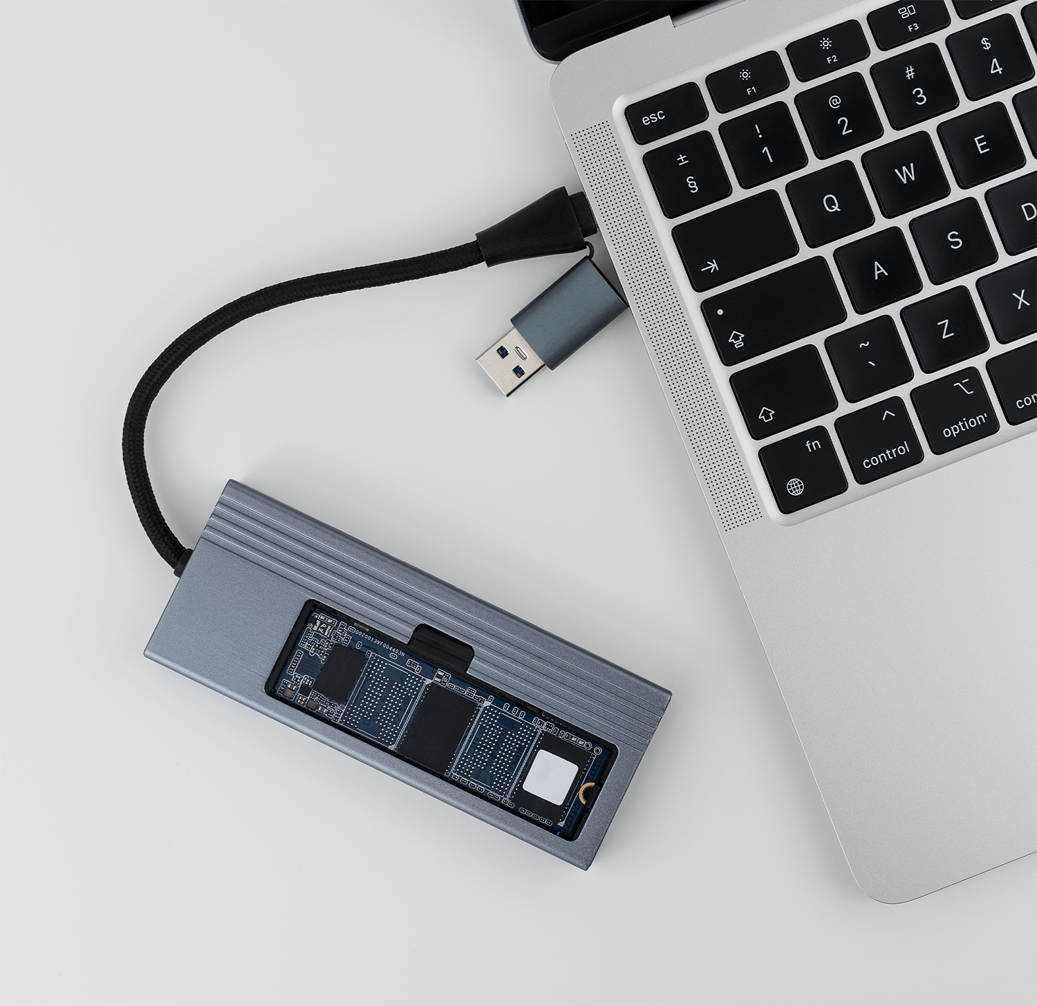 Laptop podłączony do szarego huba USB, hub częściowo rozebrany, widoczne elementy wewnętrzne.