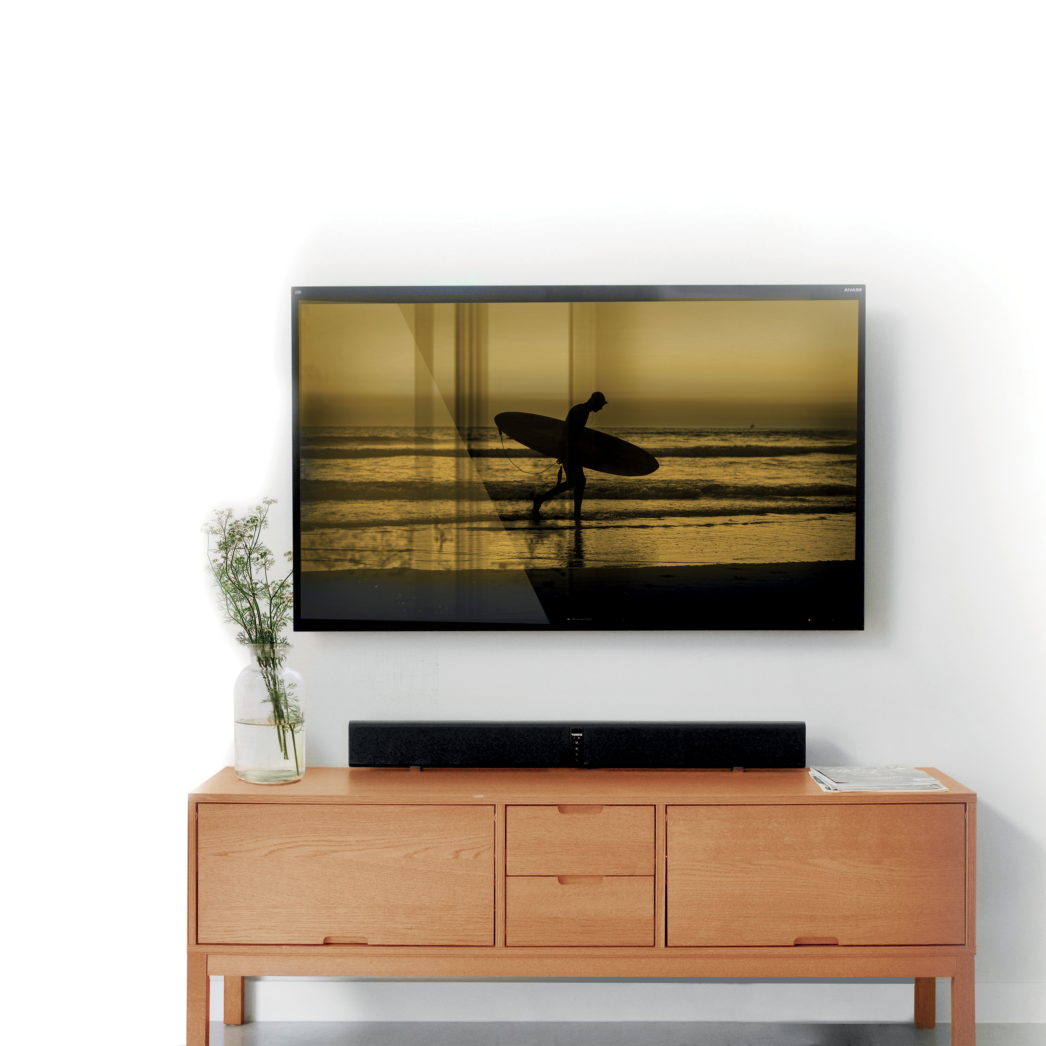 Un televisor montado en una pared blanca, mostrando una escena de surf, con una barra de sonido debajo.