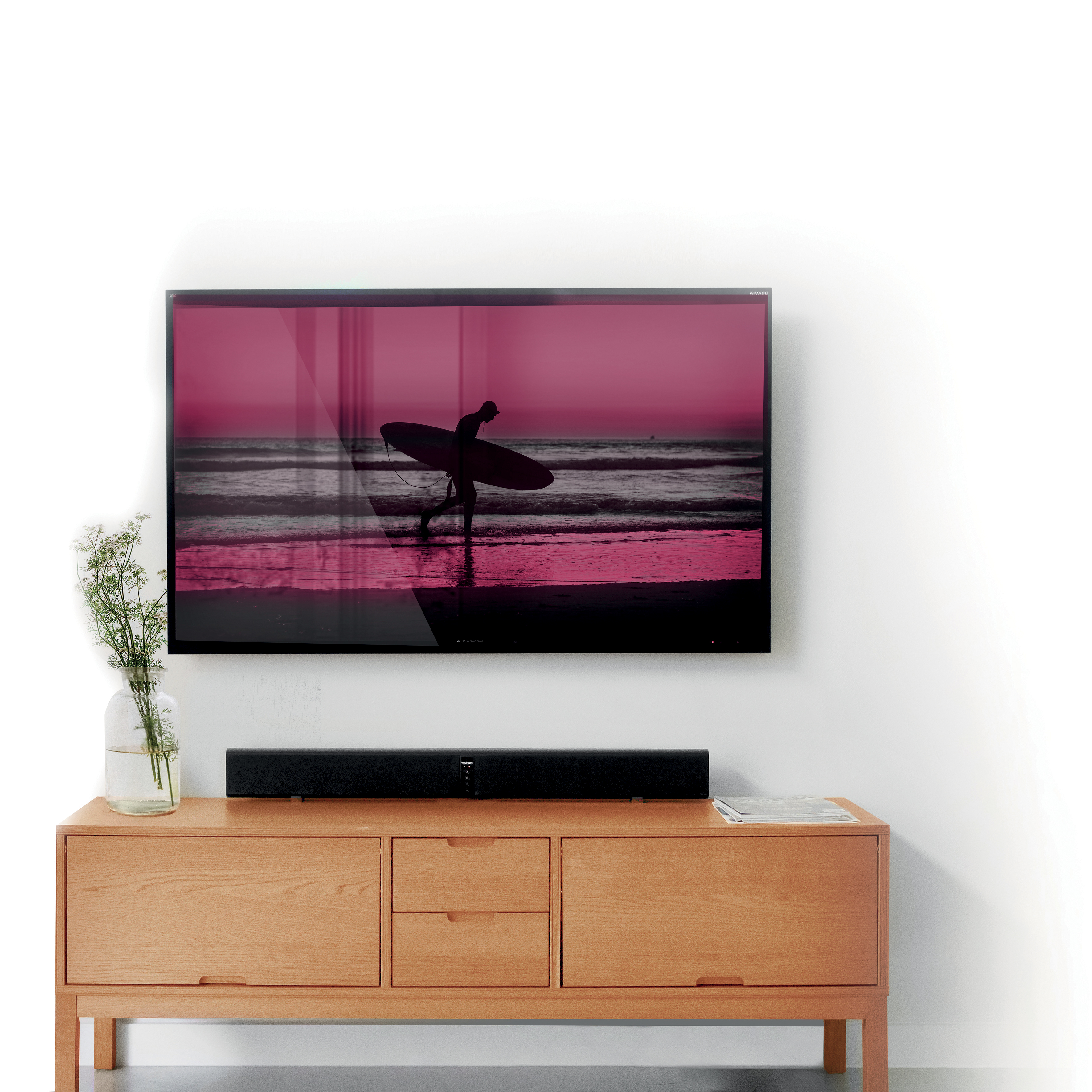 Un televisor muestra a un surfista en una playa. Cuelga sobre un mueble de madera. Una barra de sonido se encuentra debajo del televisor.